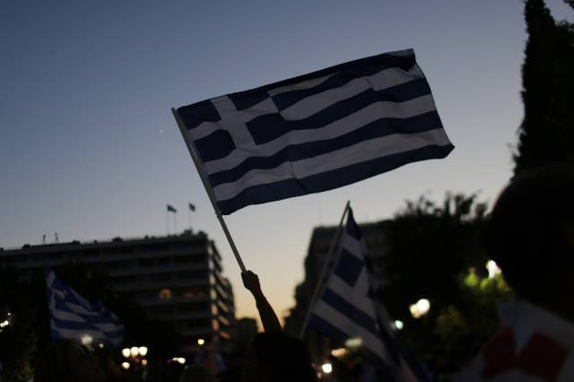Supporters of the No vote wave Greek flags after the first results of the referendum at Syntagma square in Athens, Sunday, July 5, 2015 (AP Photo/Emilio Morenatti)
