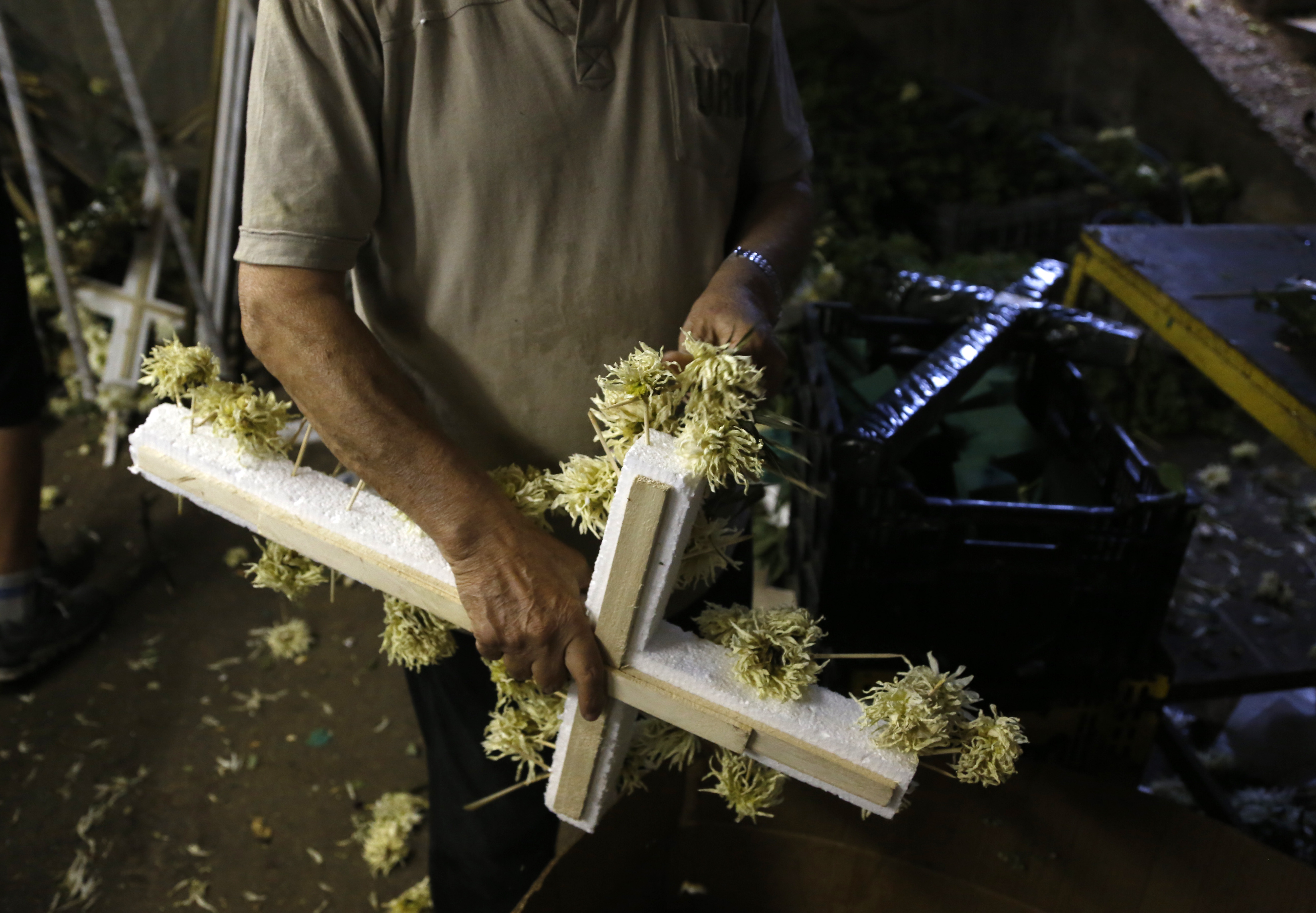 A worker removes the flowers from a wreath in Athens, Friday, July 17, 2015. Funeral homes here are struggling to cope with banking restrictions _ with a modest funeral costing more the 15 times the daily ATM withdrawal limit _ in a country that traditionally carries out funerals shortly after death and almost everything is paid for in cash. (AP Photo/Petros Karadjias) (AP)
