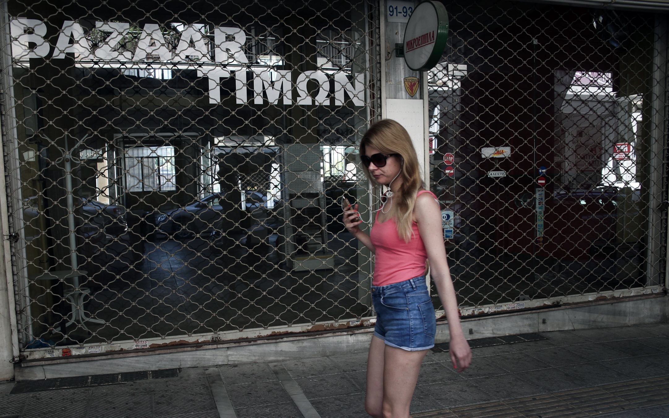 A woman passes outside a shuttered shop in Athens. News that Greece clinched a deal to stay within the eurozone group of nations broke Monday morning  . (AP)