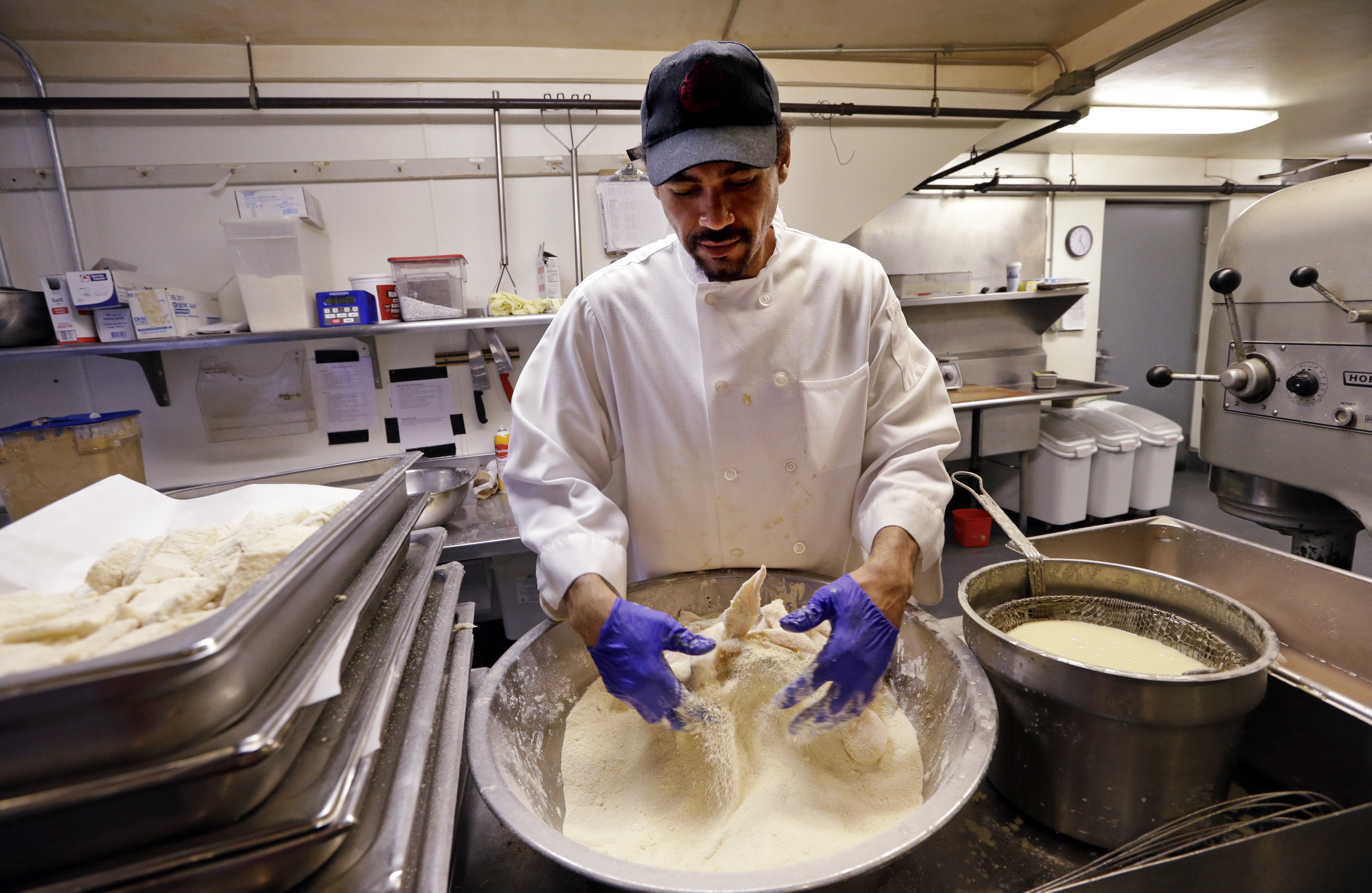In this photo taken Monday, July 27, 2015, Chikwanha Nyashanu prepares fish at an Ivar's restaurant in Seattle. After Seattle's new minimum wage law took effect last April 1, Ivars Seafood Restaurants announced that it was jacking up its prices by about 21 percent, eliminating tipping as a routine procedure, and immediately paying all its hourly workers a $15 per hour. They began the new pay rate three years earlier than the law required. (AP Photo/Elaine Thompson) (AP)