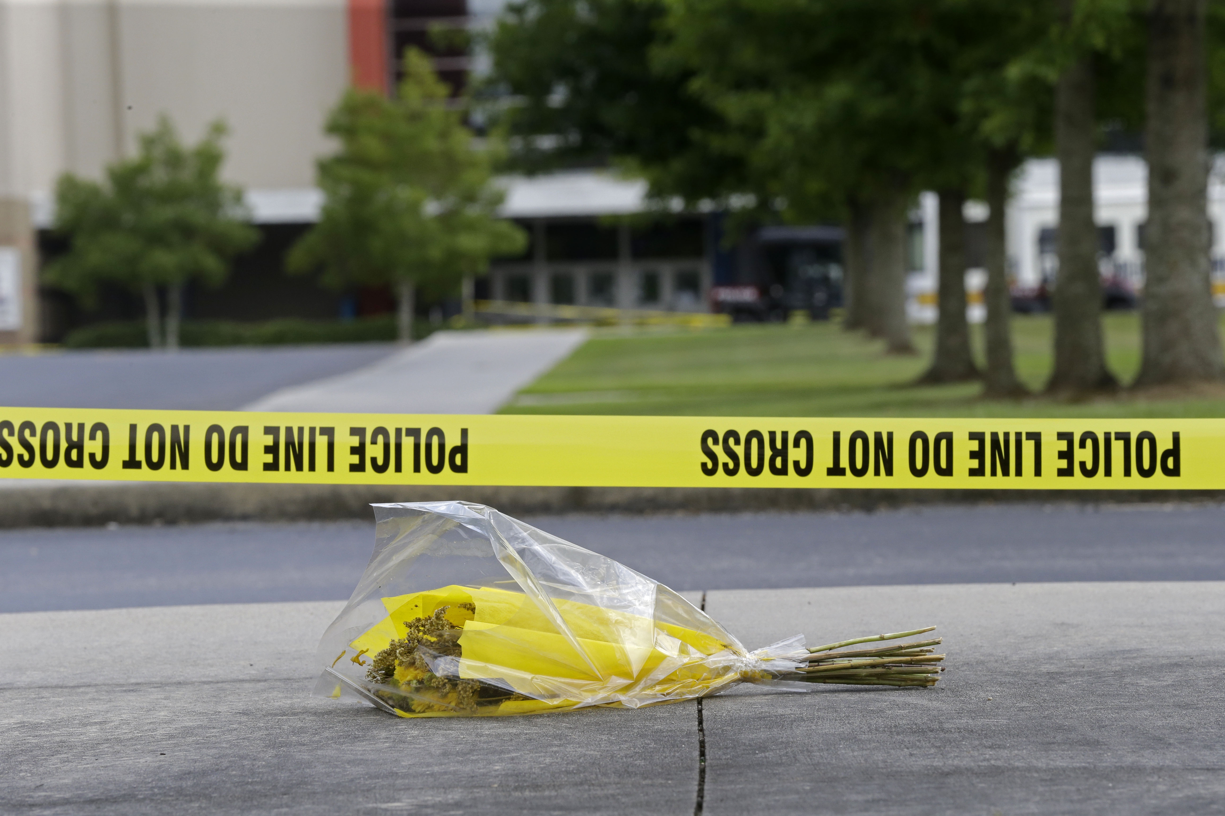 A bouquet of flowers lies net crime scene tape in the parking lot outside The Grand 16 movie theater in Lafayette, La. (AP/Gerald Herbert)