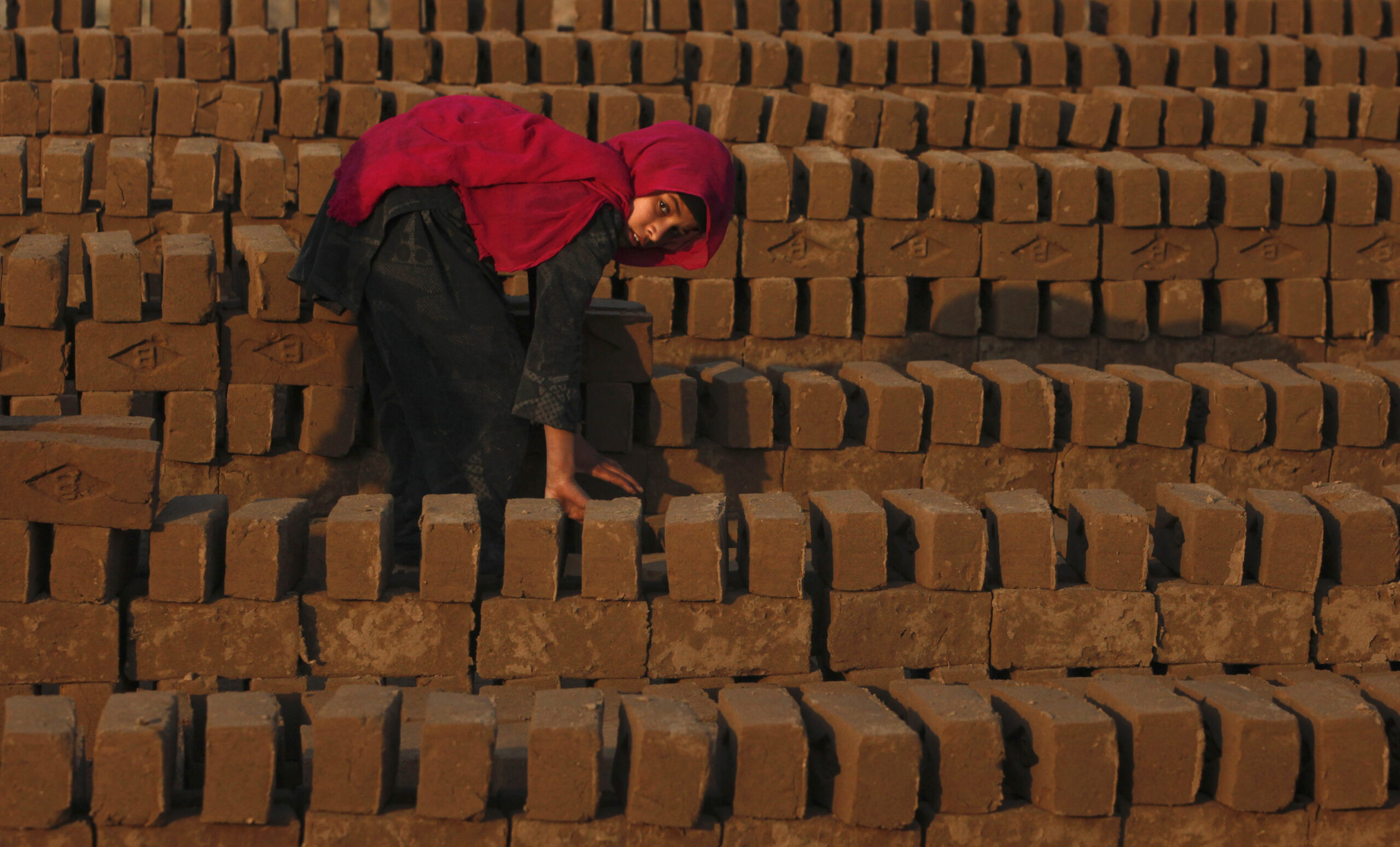 Farzeena, 12, arranges bricks to be baked in a kiln at a brickyard in the outskirts of Islamabad December 28, 2011. REUTERS/Faisal Mahmood  (PAKISTAN - Tags: BUSINESS EMPLOYMENT ENVIRONMENT) - RTR2VOPK (REUTERS/Faisal Mahmood)