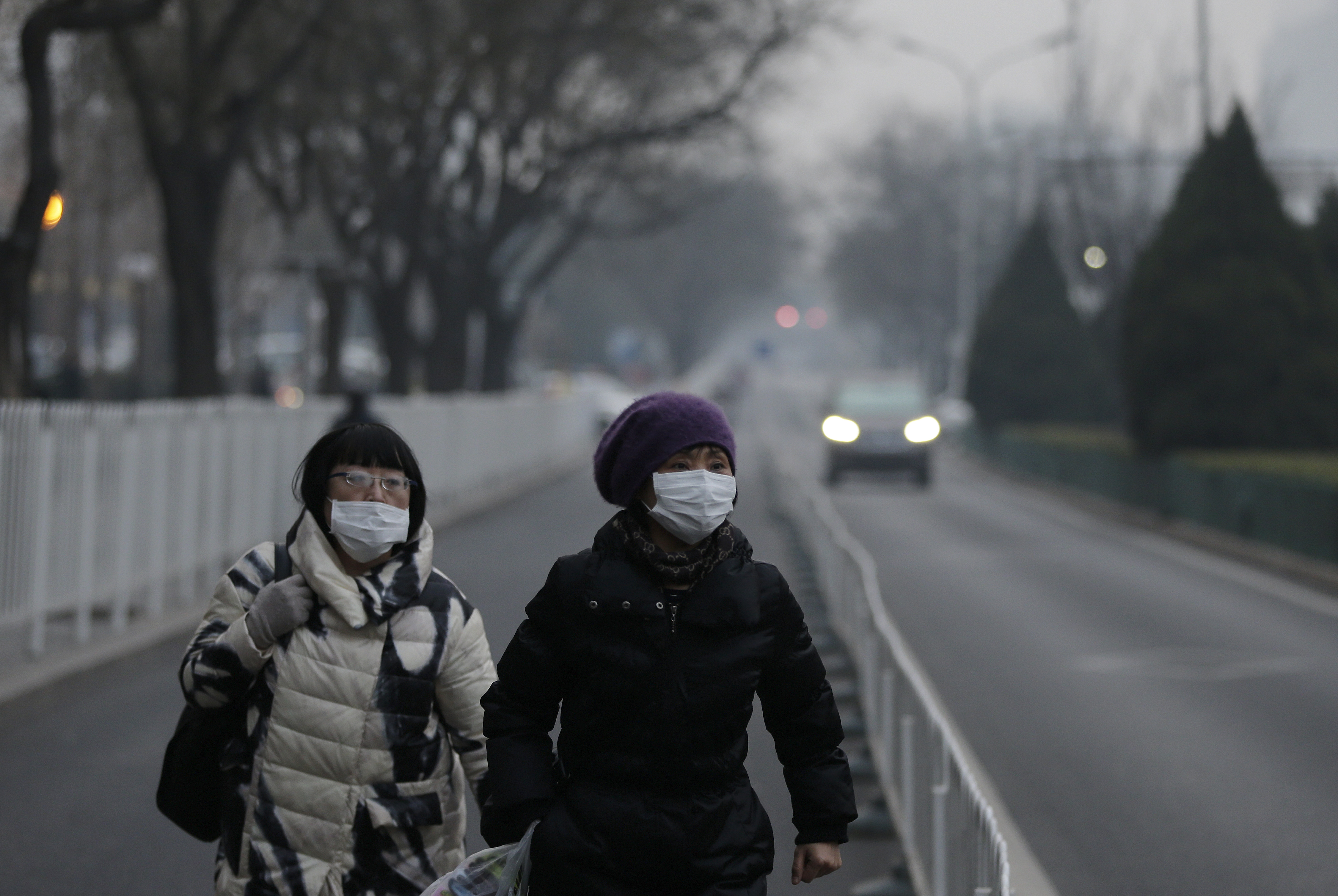 Women wear masks as they walk along a street on a polluted day in Beijing, Sunday, Dec. 13, 2015. China's push for a global climate pact is partly because of its own increasingly pressing need to solve serious environmental problems, observers said Sunday. (AP Photo/Andy Wong) (AP)