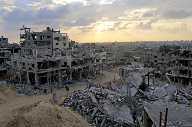 Palestinians walk through the rubble of their homes in October 2014 in Shuja'iyya, Gaza, after Israel's U.S.-backed bombing (AP/Adel Hana)