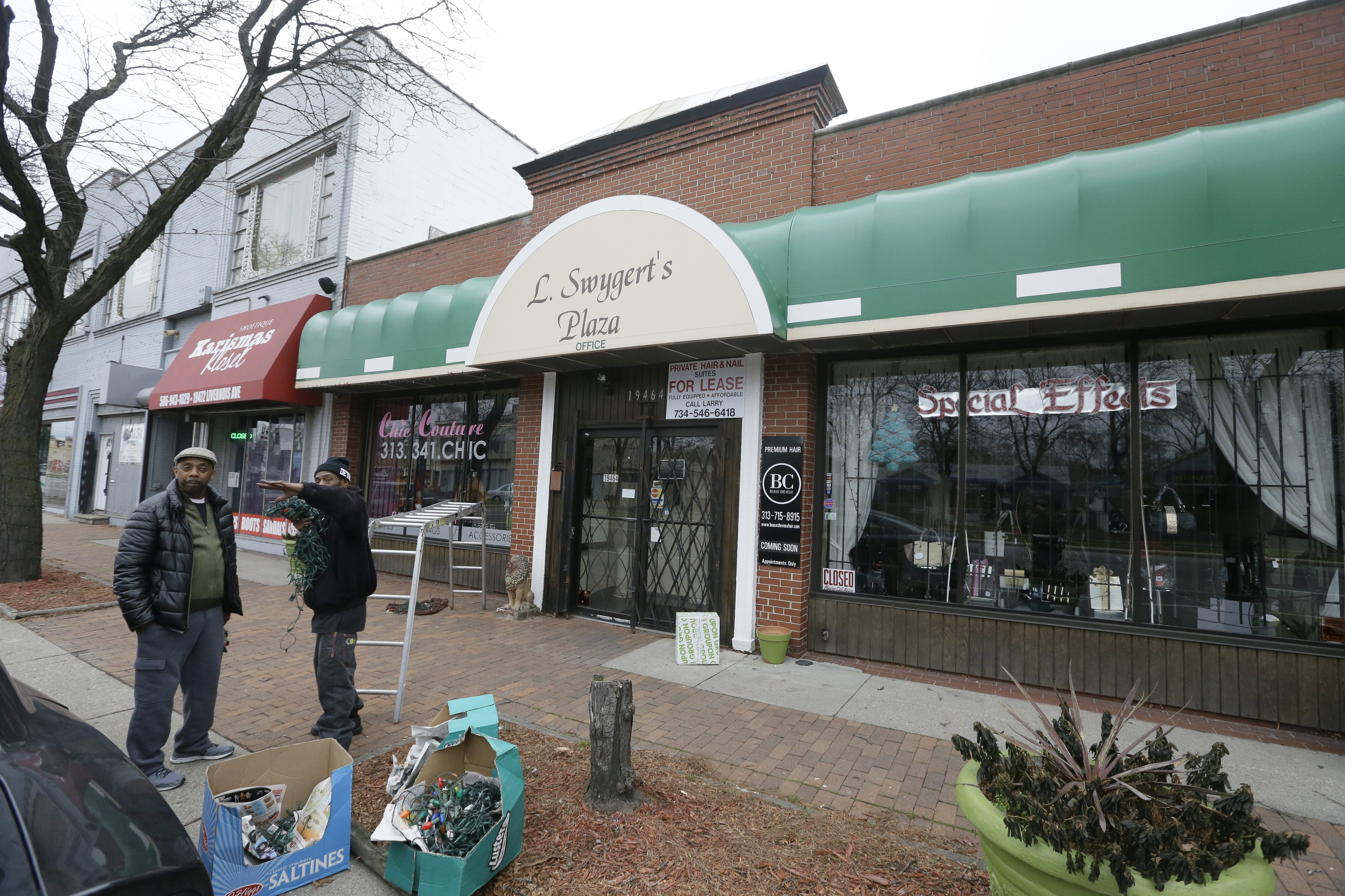 Business owner Larry Swygert, left, talks with Anthony Raynail Higgenbottom as Higgenbottom prepares to install Christmas lights on one of Swygert's buildings on Livernois Avenue, Tuesday, Dec. 15, 2015 in Detroit. The city's longtime Avenue of Fashion on the city's west side has been seeing new businesses and shoppers in recent years. The surrounding area remains one of Detroit's most stable, but the avenue lost flair as merchants closed or moved to suburbs and malls. The boulevard seeks its own vibe through one-of-a-kind apparel shops, restaurants and art galleries. () (AP Photo/Carlos Osorio)