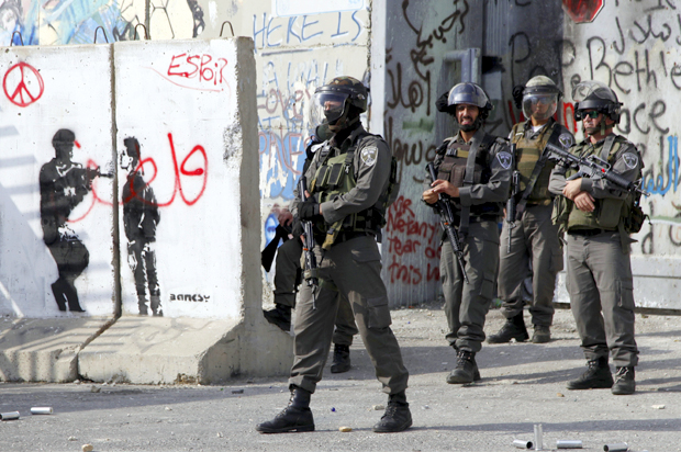 Israeli border policemen stand in front of the West Bank side of the check point between Jerusalem and Bethlehem during clashes with Palestinian demonstrators Friday, Oct. 2, 2015. (AP/Mahmoud Illean)