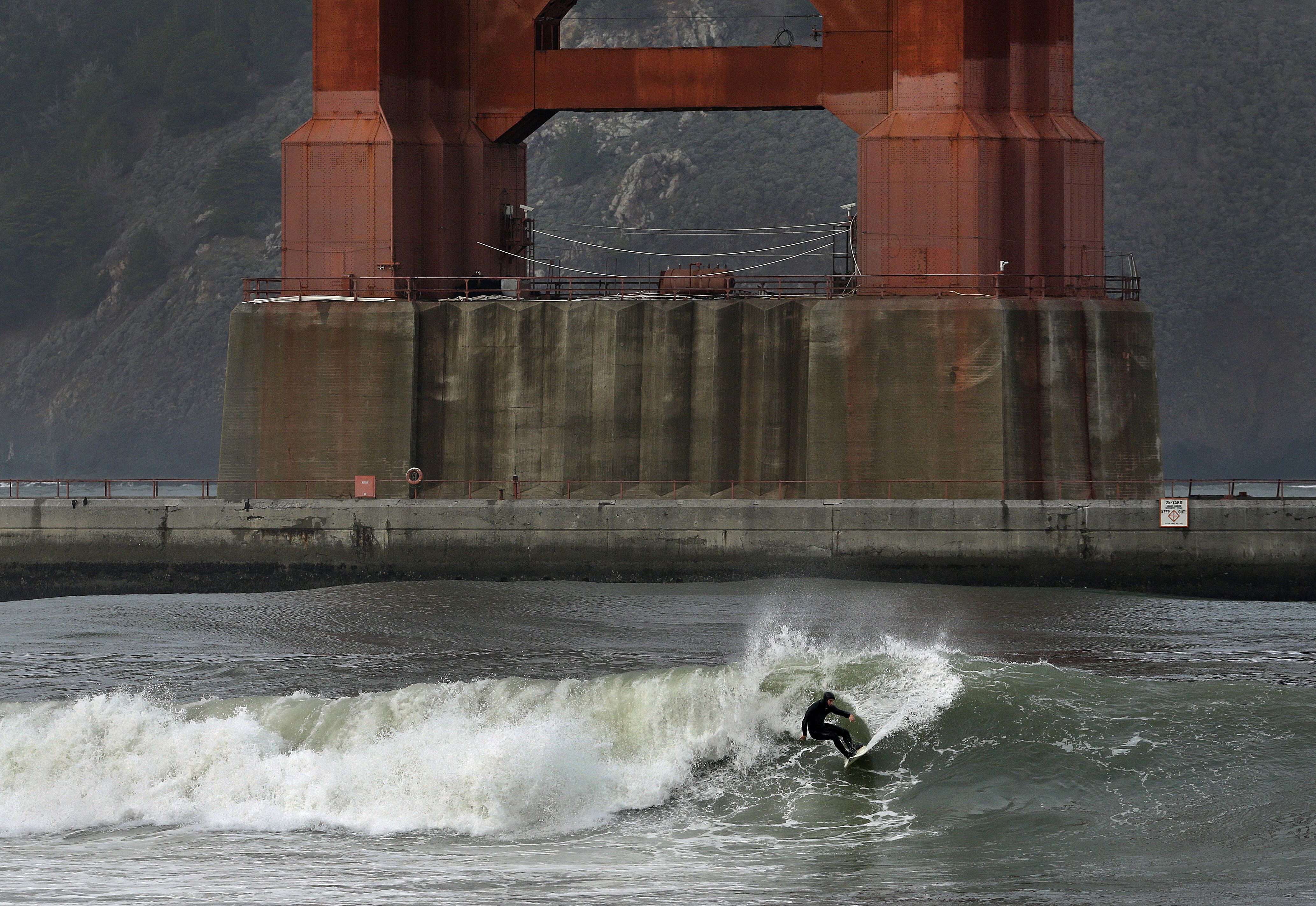 A surfer rides a wave, churned by a winter storm, breaking underneath the south tower of the Golden Gate Bridge, Wednesday, Jan. 6, 2016, in San Francisco Bay. El Nino storms lined up in the Pacific promise to drench parts of the West for more than two weeks and increase fears of mudslides and flash floods in regions stripped bare by wildfires. (AP Photo/Ben Margot) (AP)