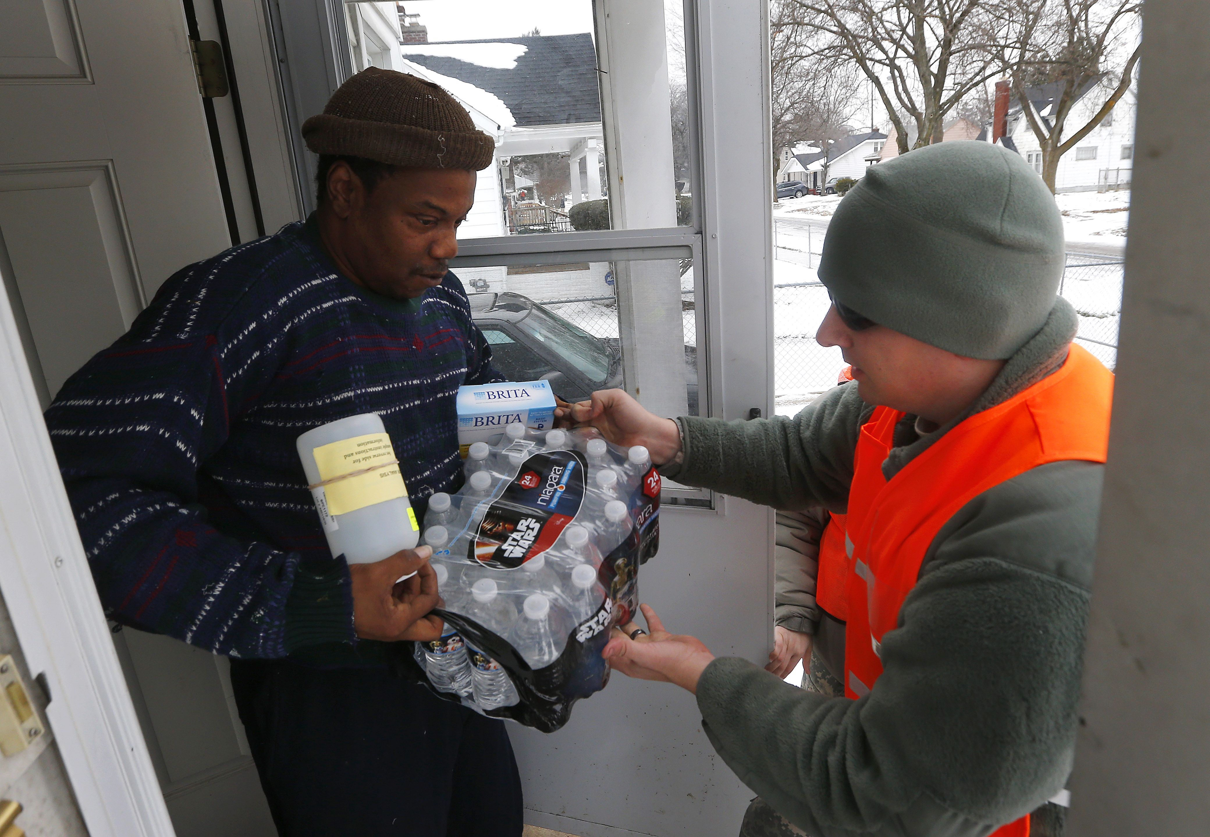 Louis Singleton receives water filters, bottled water and a test kit from Michigan National Guard Specialist Joe Weaver as clean water supplies are distributed to residents, Thursday, Jan. 21, 2016 in Flint, Mich. The National Guard, state employees, local authorities and volunteers have been distributing lead tests, filters and bottled water during  the city's drinking water crisis.  (AP Photo/Paul Sancya) (AP)