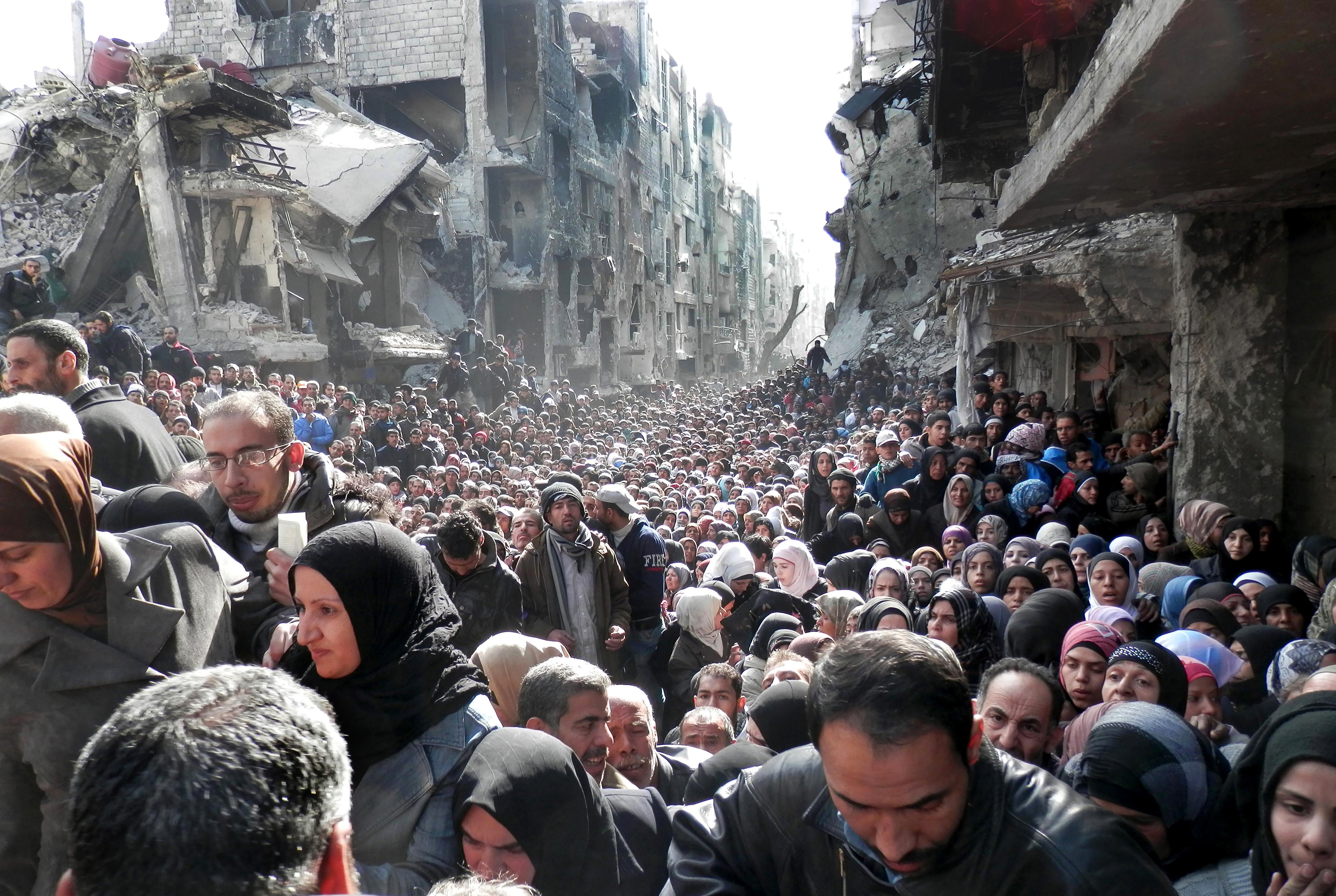 FILE - In this Jan. 31, 2014 file photo released by the United Nations Relief and Works Agency for Palestine Refugees in the Near East (UNRWA), shows residents of the besieged Palestinian camp of Yarmouk, queuing to receive food supplies, in Damascus, Syria. That year, the U.N. was able to deliver food to about five percent of people in besieged areas including Yarmouk, while today estimates show the organization is reaching less than one percent.(UNRWA via AP, File) (AP)