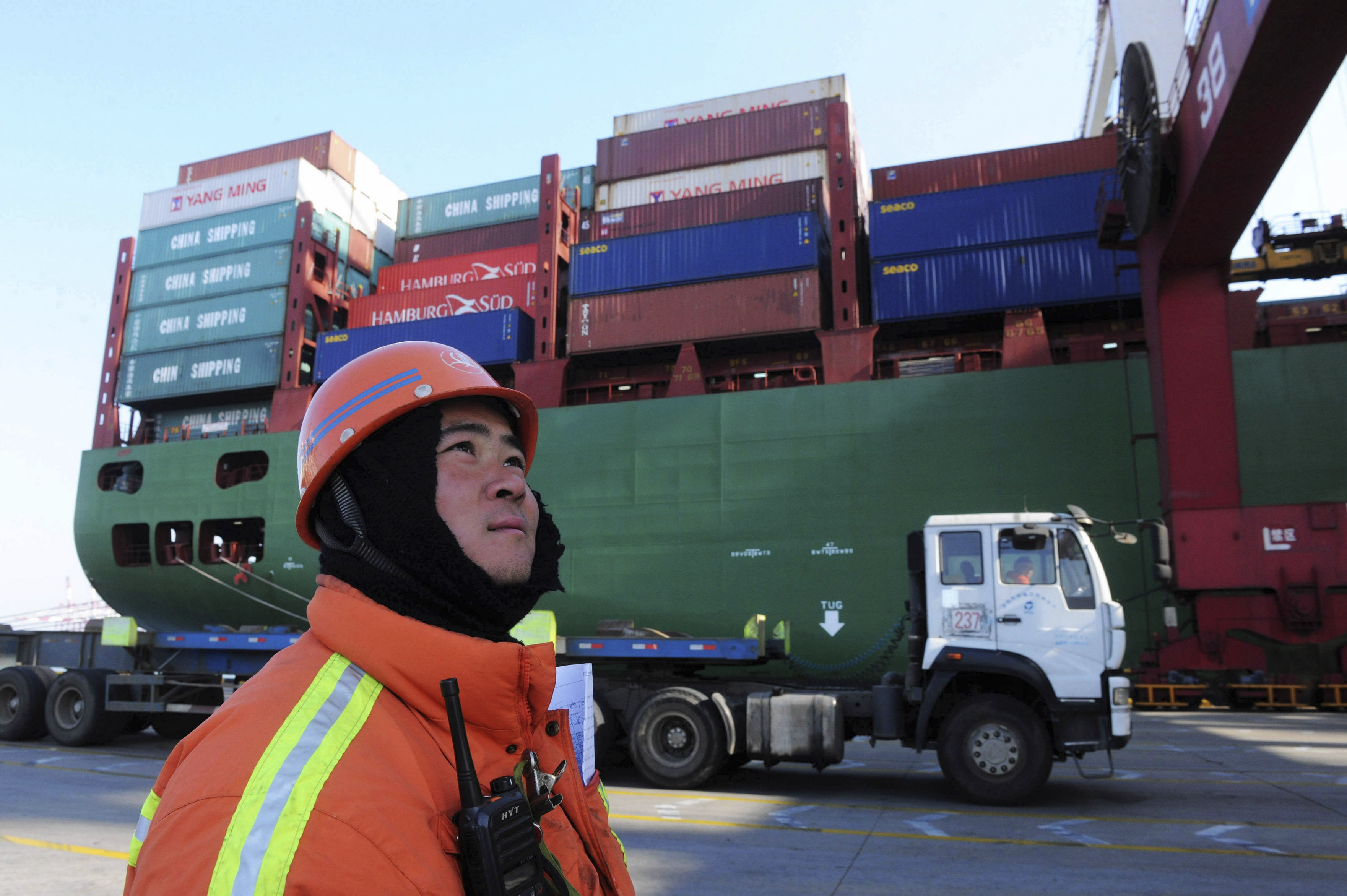 A port worker stands near a container ship at a port in Qingdao in eastern China's Shandong province Monday Feb. 15, 2016. (Chinatopix Via APCHINA OUT)