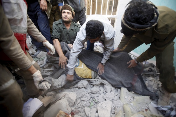 Yemeni police and medics cover the body of a dead man after the Saudi-led coalition bombed the police headquarters in Yemen's capital Sanaa, on January 18, 2016 (Reuters/Khaled Abdullah)