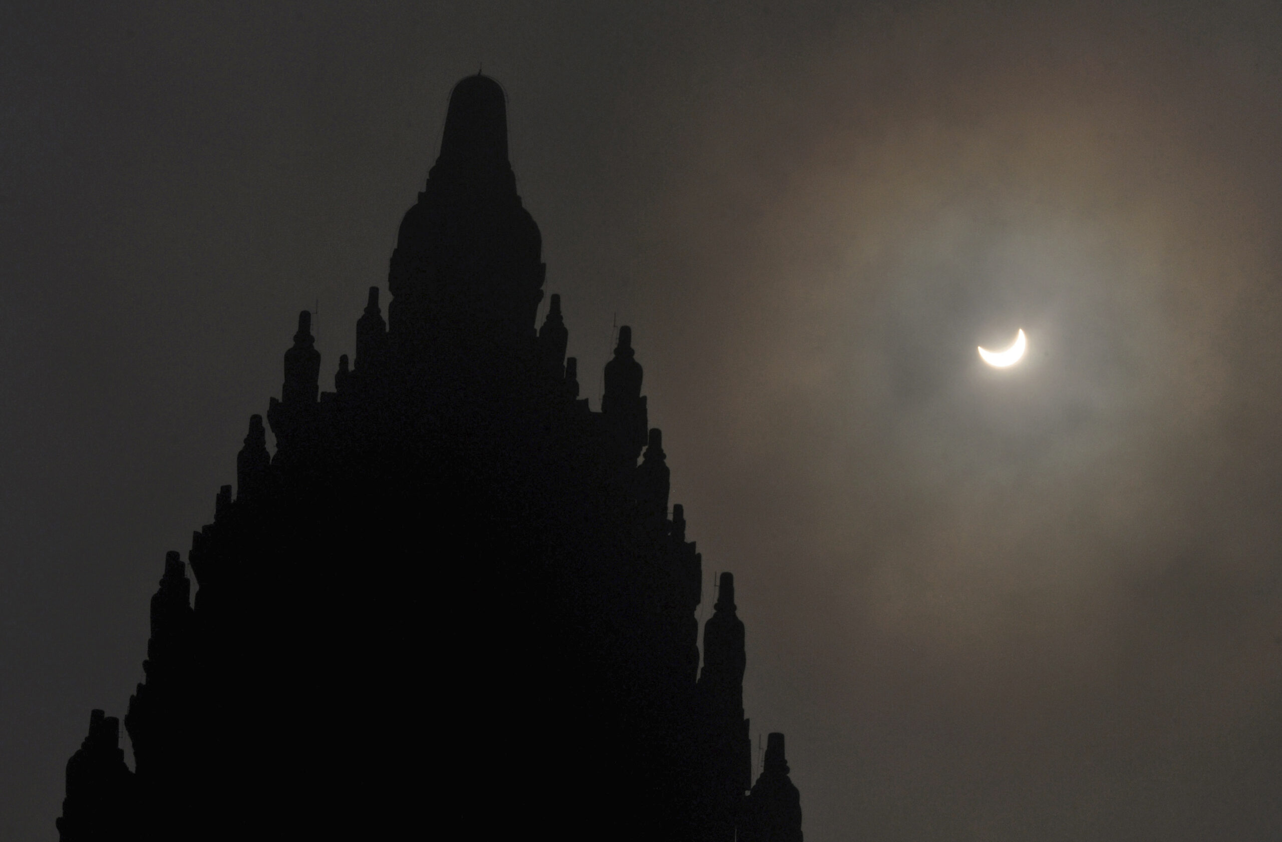 A partial solar eclipse is seen behind the 9th century Prambanan Temple in Yogyakarta, Indonesia, Wednesday, March 9, 2016. The rare astronomical event is being witnessed Wednesday along a narrow path that stretches across 12 provinces encompassing three times zones and about 40 million people. (AP Photo/Slamet Riyadi) (AP)