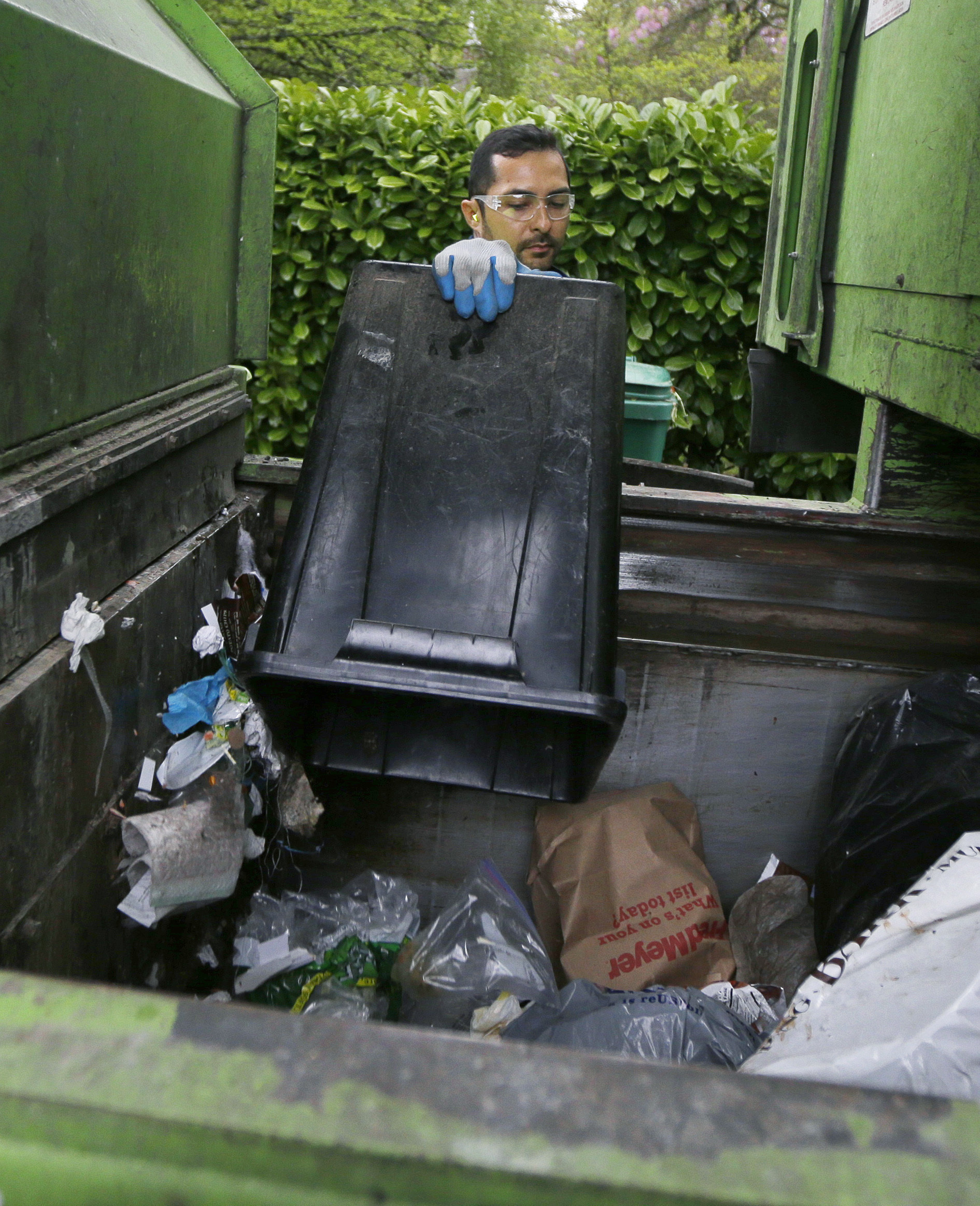 David Morales, a garbage driver with Recology, dumps a garbage container for Seattle Public Utilities, Friday, April 15, 2016, in Seattle. A judge is scheduled to hear a challenge Friday, April 16, 2016, to a new Seattle law allowing garbage collectors to check people's trash to see whether they are disposing of recycling items and food waste incorrectly.  (AP Photo/Ted S. Warren) (AP)