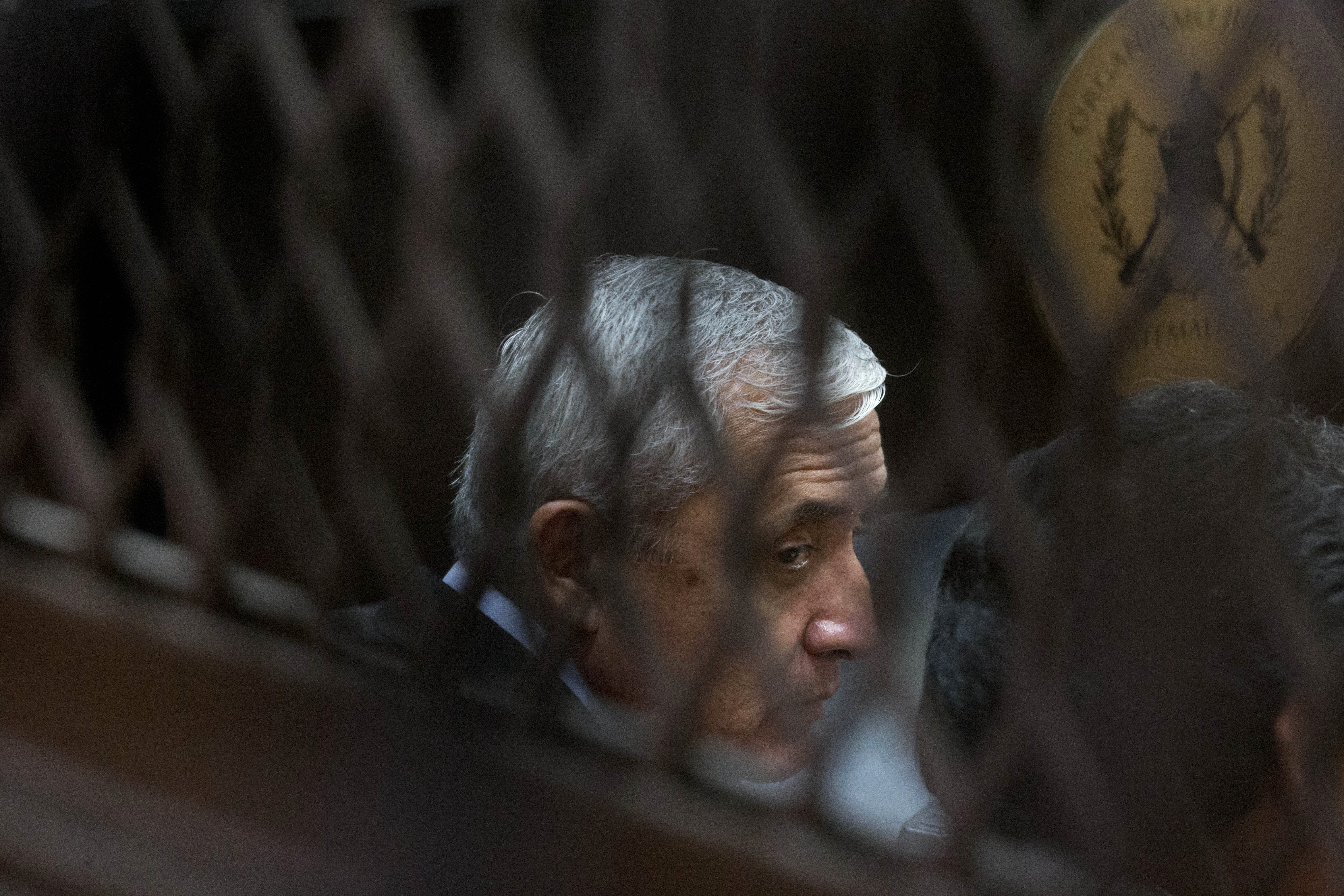 FILE - In this Sept. 8, 2015 file photo, Guatemala's former President Otto Perez Molina, photographed through a window, sits in court for a third hearing on corruption allegations that led him to resign, in Guatemala City. (AP Photo/Esteban Felix, File))