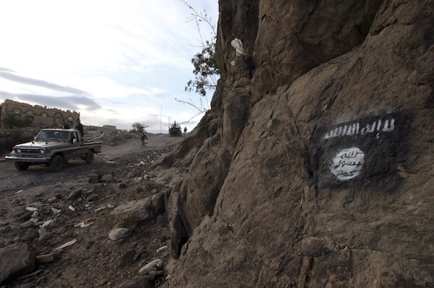 Houthi rebels drive a patrol truck past a flag of Ansar al-Sharia, the local wing of al-Qaeda in the Arabian Peninsula (AQAP) in Rada, Yemen on November 22, 2014 (Reuters/Mohamed al-Sayaghi)