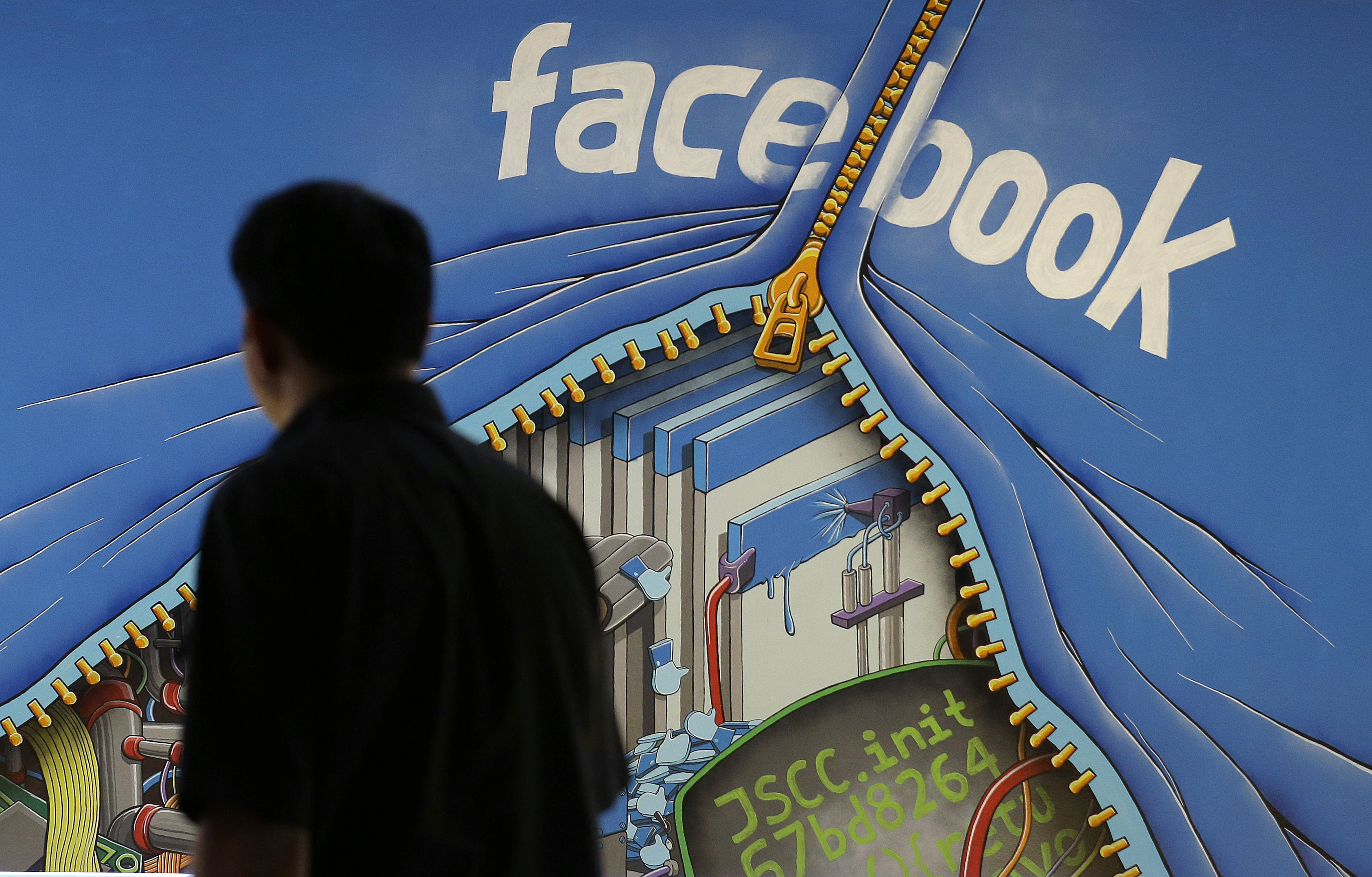 FILE - In this June 11, 2014, file photo, a man walks past a mural in an office on the Facebook campus in Menlo Park, Calif. On Thursday, May 12, 2016, Facebook pulled back the curtain on how its Trending Topics feature works, a reaction to a report that suggested Facebook downplays conservative news subjects. (AP Photo/Jeff Chiu, File) (AP)