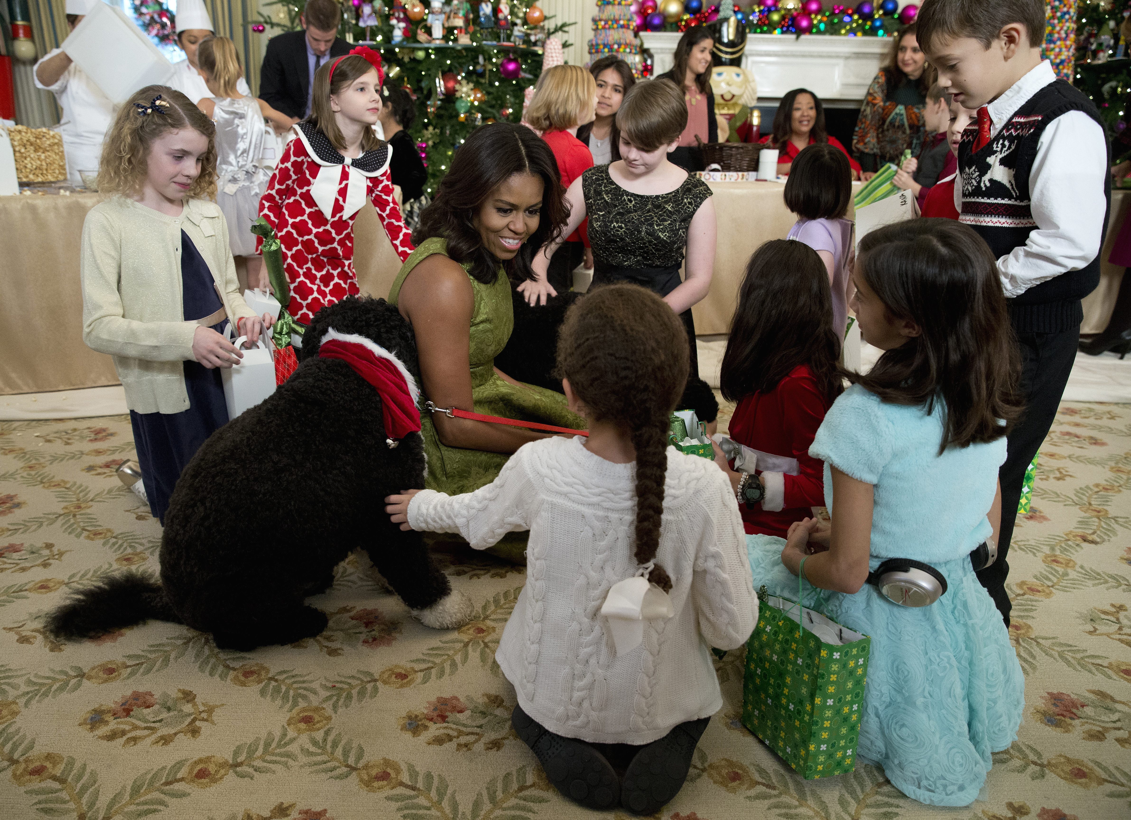 FILE - In this Dec. 2, 2015, file photo, first lady Michelle Obama with dogs Bo, left, and Sunny, behind at right, are surrounded by children in the State Dining Room of the White House in Washington. (AP)