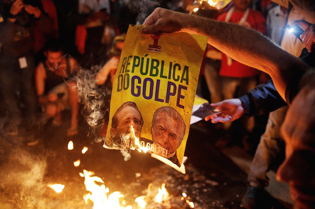 Brazilian activists burn a poster reading "Republic of the Coup," with the images of Senate President Renan Calheiros (L) and right-wing interim President Michel Temer, at a protest in Sao Paulo, Brazil on May 12, 2016 (Reuters/Nacho Doce)