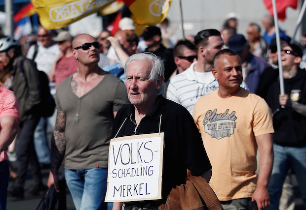 A German man holds a sign with the Nazi propaganda term "Volksschädling" (enemy of the people) at a right-wing protest against refugees, Islam and Chancellor Angela Merkel in Berlin, Germany on May 7, 2016 (Reuters/Hannibal Hanschke)