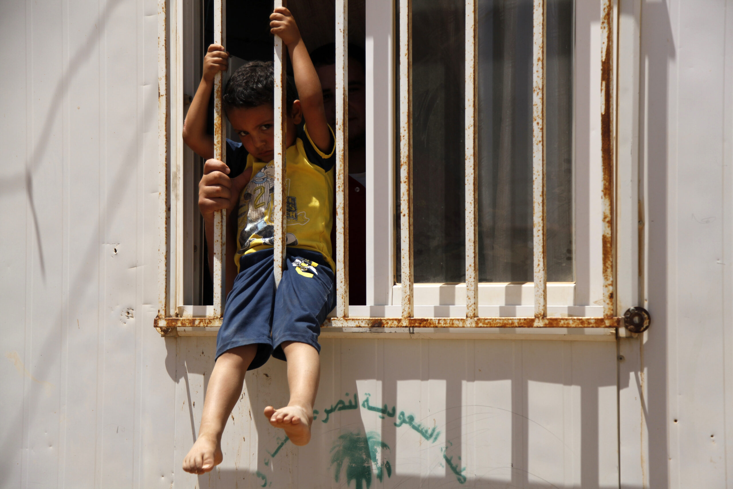 A man holds a child in the window of a shelter at the Zaatari refugee camp in northern Jordan, Sunday, June 19, 2016. Since the start of the Syrian war, 4.8 million people have fled the country, with 655,000 taking refugee in country, 80,000 of which reside in Zaatari, the largest of Jordan's three refugee camps. (AP Photo/Sam McNeil) (AP)