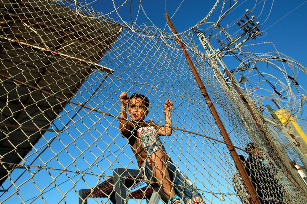 A Palestinian boy stands behind a fence in the southern Gaza Strip, May 12, 2016. (Reuters/Suhaib Salem)