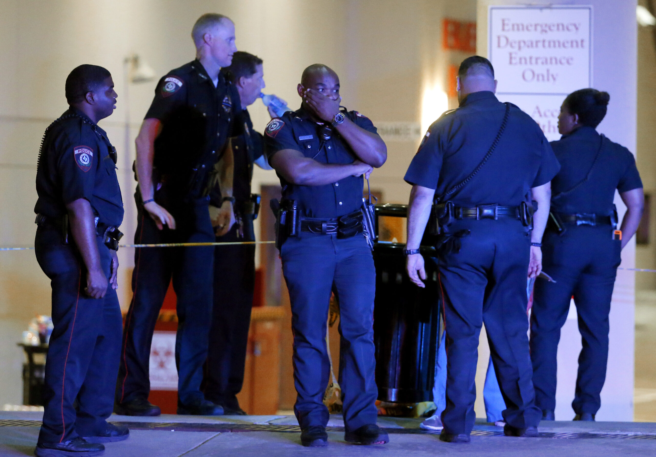 A Dallas police officer covers his face as he stands with others outside the emergency room at Baylor University Medical Center  in Dallas. (AP)