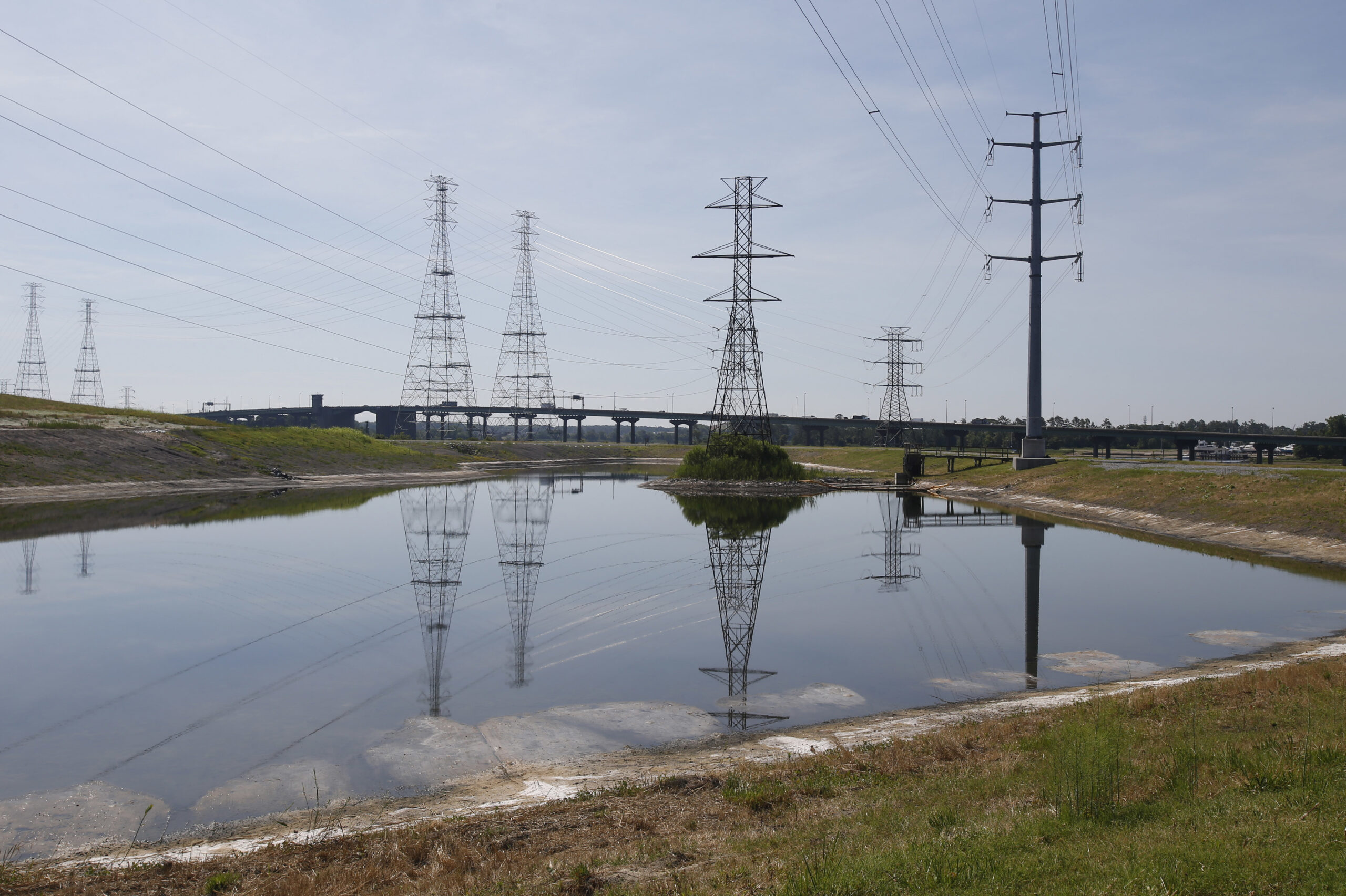 Power lines tower over a coal ash pond from an abandoned coal fired power plant in Chesapeake, Va., Monday, June 27, 2016. A lawsuit has gone to a judge over environmentalists claim that there are leaks of arsenic and other heavy metals into a river near Dominion's abandoned Chesapeake power plant in violation of the Clean Water Act. (AP Photo/Steve Helber) (AP)