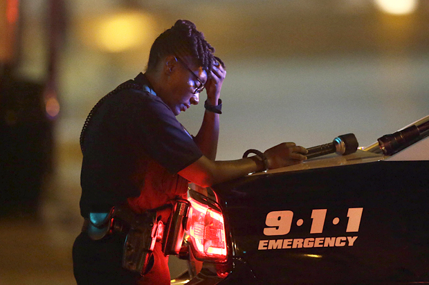 A Dallas police officer, who did not want to be identified, takes a moment as she guards an intersection in the early morning after a shooting in downtown Dallas, July 8, 2016. (AP/LM Otero)