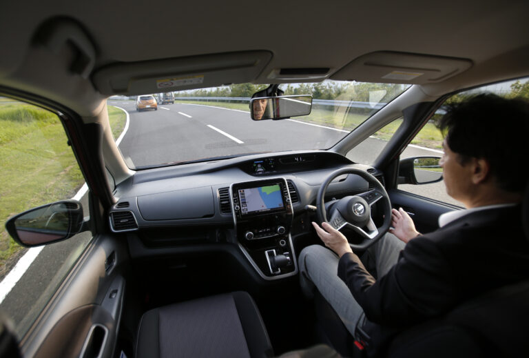 In this July 12, 2016 photo, Nissan Motor Co. Deputy General Manager Atsushi Iwaki gets his hands off of the steering wheel of a self-driving new Serena minivan during a test drive at Nissan test course in Yokosuka, near Tokyo. (AP Photo/Shizuo Kambayashi)