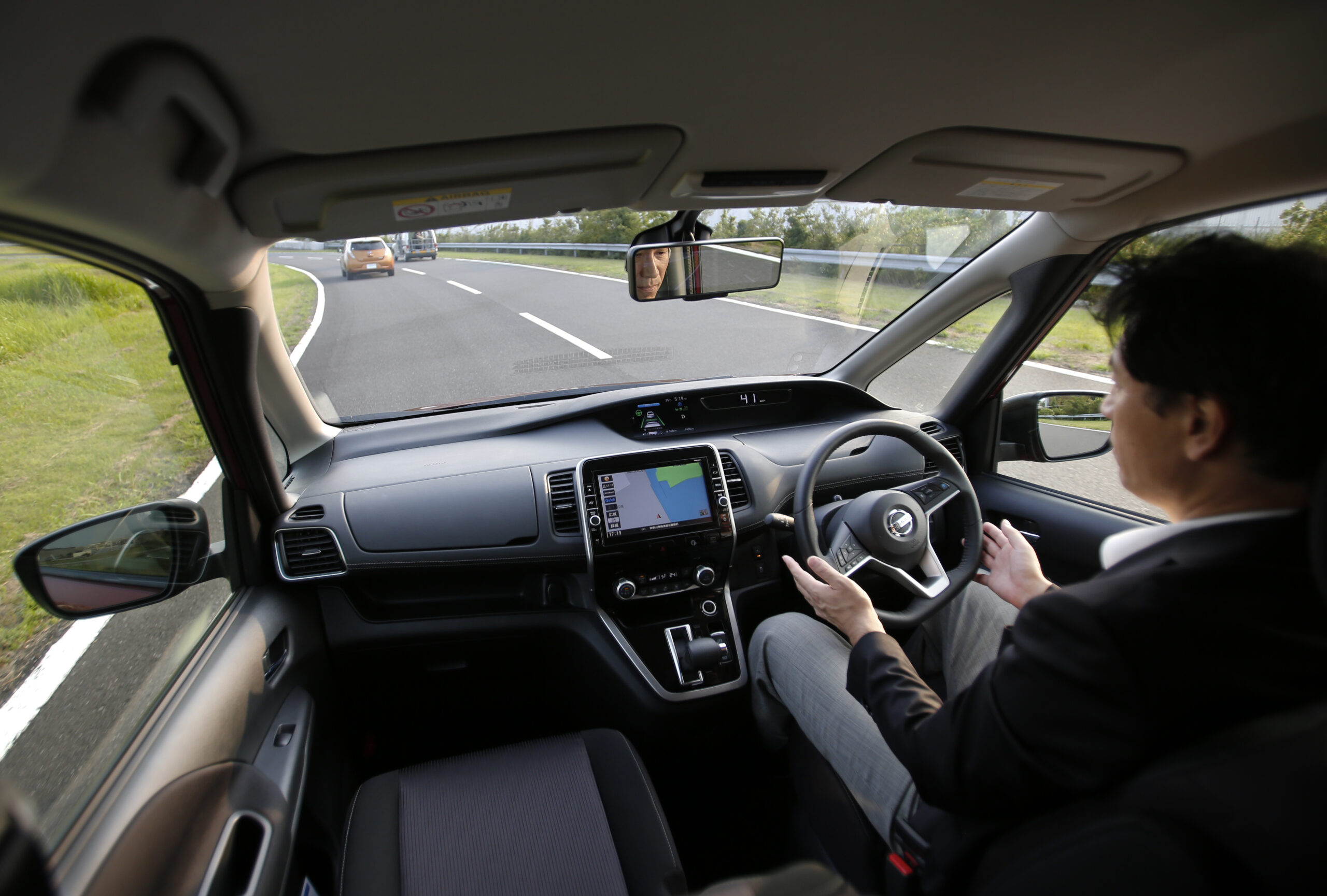 In this July 12, 2016 photo, Nissan Motor Co. Deputy General Manager Atsushi Iwaki gets his hands off of the steering wheel of a self-driving new Serena minivan during a test drive at Nissan test course in Yokosuka, near Tokyo. (AP Photo/Shizuo Kambayashi)