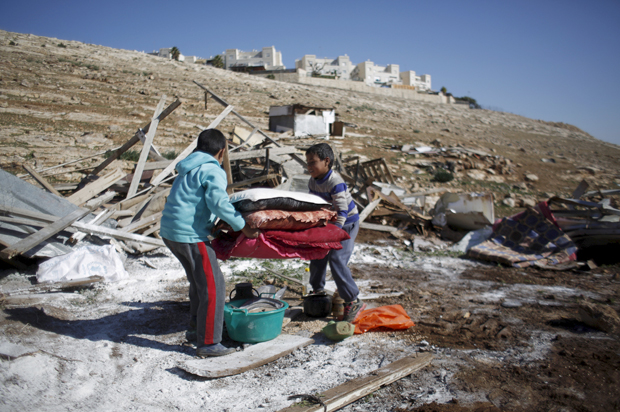 Palestinian boys carry their belongings after the Israeli army demolished their shanty, near the Israeli West Bank settlement of Maale Adumim, January 6, 2016. (Reuters/Mohamad Torokman)