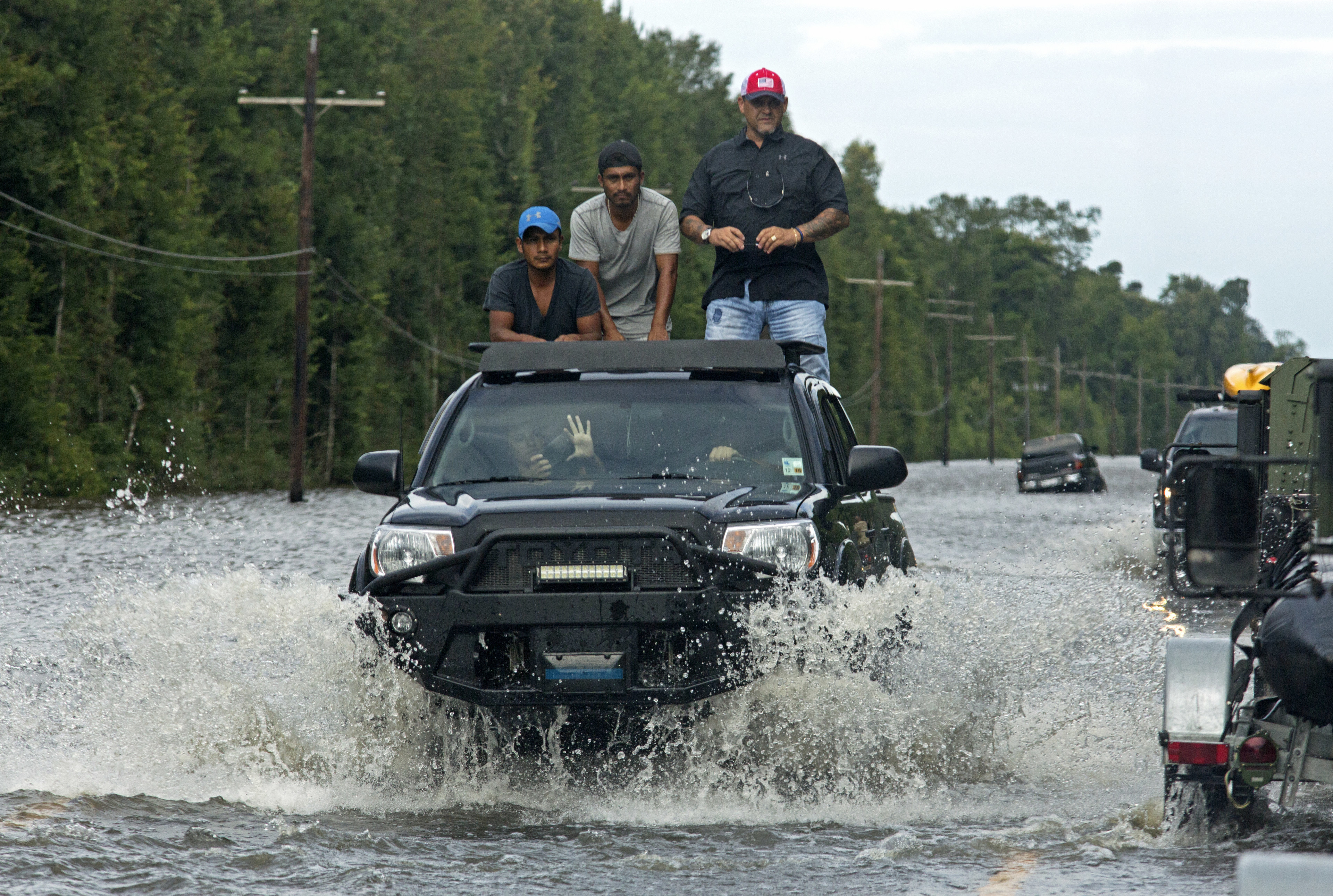 Motorists on Highway 190 drive through deep water through Holden, La., Sunday, Aug. 14, 2016. (AP Photo/Max Becherer)
