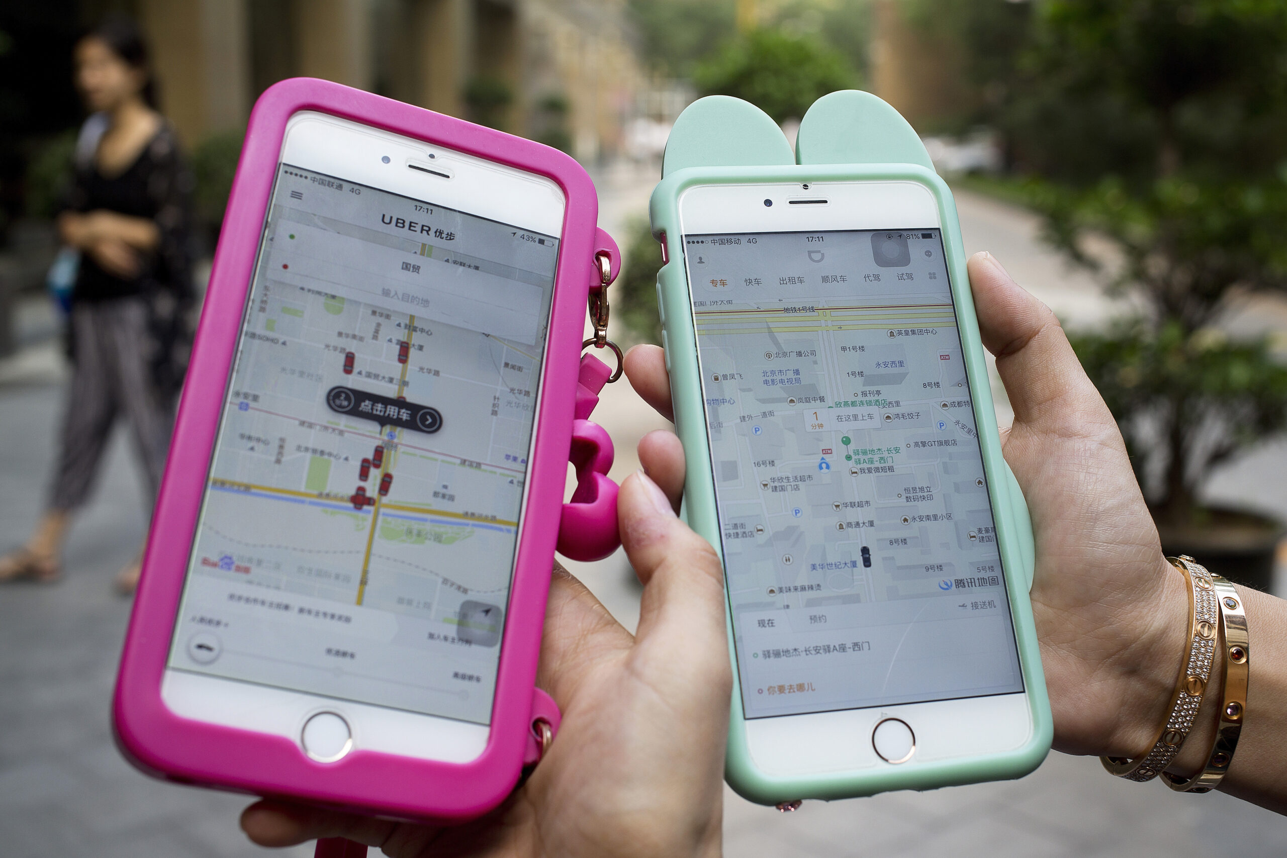 Women holding their smartphones show the ride-hailing apps Uber Technology Ltd., left, and Didi Chuxing at a residential compound in Beijing, Monday, Aug. 1, 2016. Uber Technology's main Chinese rival, Didi Chuxing, says it is acquiring the U.S. ride-hailing service's China operations, linking the companies in a business alliance after a costly battle for market share. Monday's announcement marked a surrender by another foreign technology brand to intense competition in China. (AP Photo/Andy Wong) (AP Photo/Andy Wong)