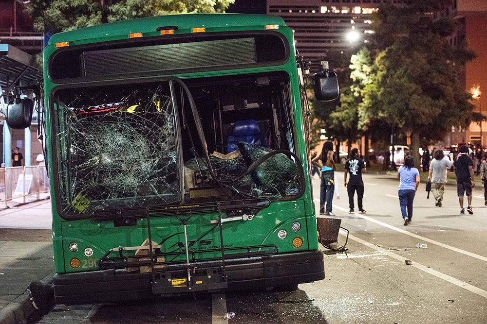 CHARLOTTE, NC - SEPTEMBER 22: Demonstrators walk near a damaged bus on September 22, 2016 in downtown Charlotte, NC. The North Carolina governor has declared a state of emergency in the city of Charlotte after clashes during protests in the city in response to the fatal shooting by police officers of 43-year-old Keith Lamont Scott at an apartment complex near UNC Charlotte. (Photo by Sean Rayford/Getty Images) (Getty Images)