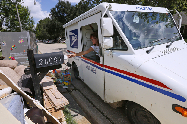 A United States Postal Service worker delivers mail to a flood damaged neighborhood in Denham Springs, Louisiana, August 23, 2016. (Reuters/Jonathan Bachman)