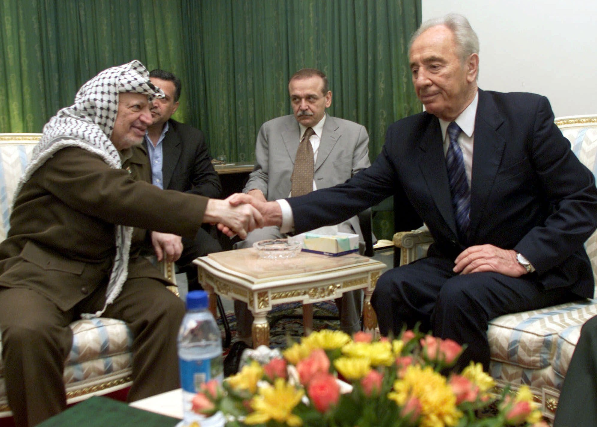 FILE - In this Sept. 26, 2001, file photo, Israeli Foreign Minister Shimon Peres, right, and Palestinian leader Yasser Arafat shake hands during their meeting at the Gaza International Airport. (AP)