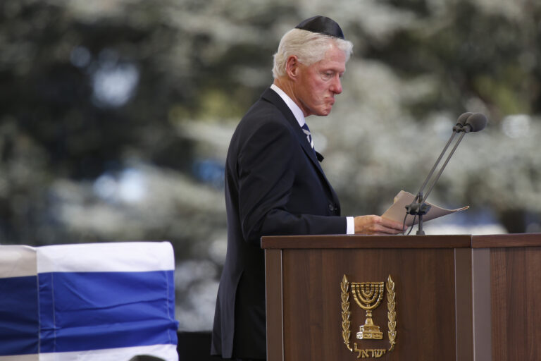Former US President Bill Clinton passes the flag-draped coffin of former Israeli President Shimon Peres during his funeral at the Mount Herzel national cemetery in Jerusalem, Friday, Sept. 30, 2016. (AP Photo/Ariel Schalit) (AP)