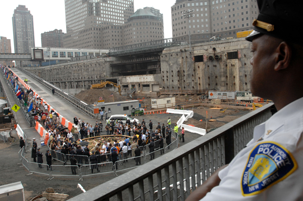 A Port Authority police officer watches the ceremony as victims' families walk down the ramp to place flowers in the reflecting pool during the ceremony on Sept. 11, 2007. (AP/Susan Watts)