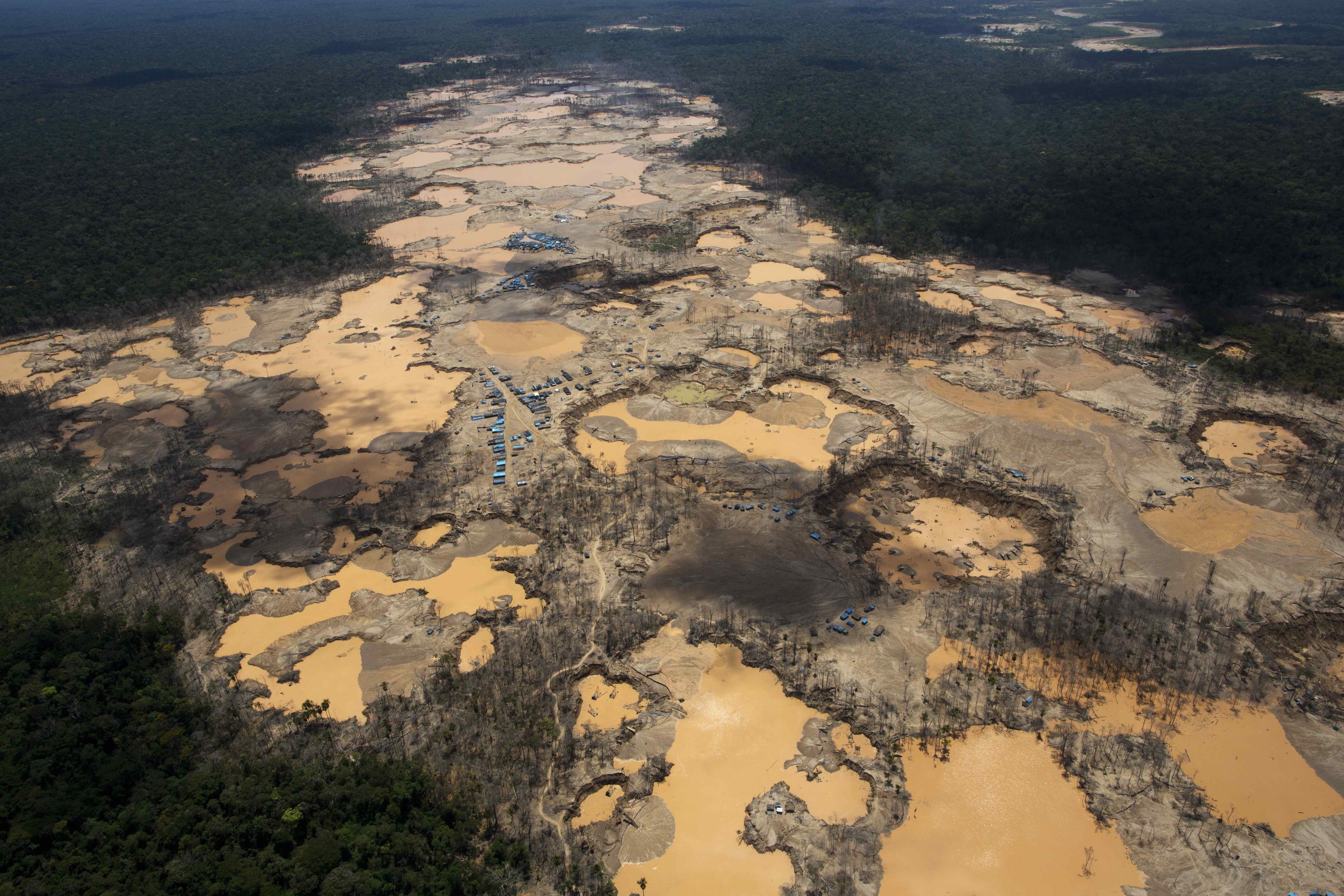 FILE - This Nov. 11, 2014 file photo shows a deforested area dotted with blue tarps, marking the area where miners reside, and craters filled with water, caused by illegal gold mining activities, in La Pampa, in Peru's Madre de Dios region. Peru's government declared an emergency across a broad jungle region because of mercury contamination, much of it caused by wildcat gold mining. Photographer Rodrigo Abd of The Associated Press and three other journalists in Brazil, Colombia and El Salvador won the 2016 Maria Moors Cabot Prize, which recognizes excellence in coverage of Latin America and the Caribbean. (AP Photo/Rodrigo Abd, File) (AP)