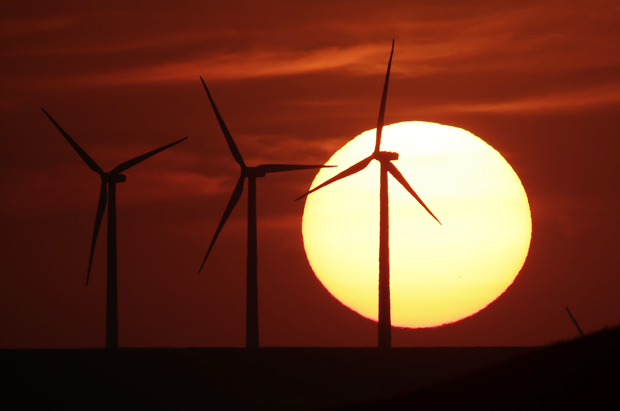 FILE - In this Aug. 23, 2013 file photo, wind turbines are silhouetted by the setting sun as they produce electricity near Beaumont, Kan. Energy independence has been a goal of every president since Richard Nixon. Hillary Clinton and Donald Trump have very different ways to achieve it. How energy is produced and where it comes from affect jobs, the economy and the environment. (AP Photo/Charlie Riedel, File) (AP)