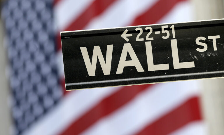 In this Tuesday, Sept. 8, 2015, file photo, a Wall Street street sign is framed by an American flag hanging on the facade of the New York Stock Exchange. (AP Photo/Mary Altaffer, File)