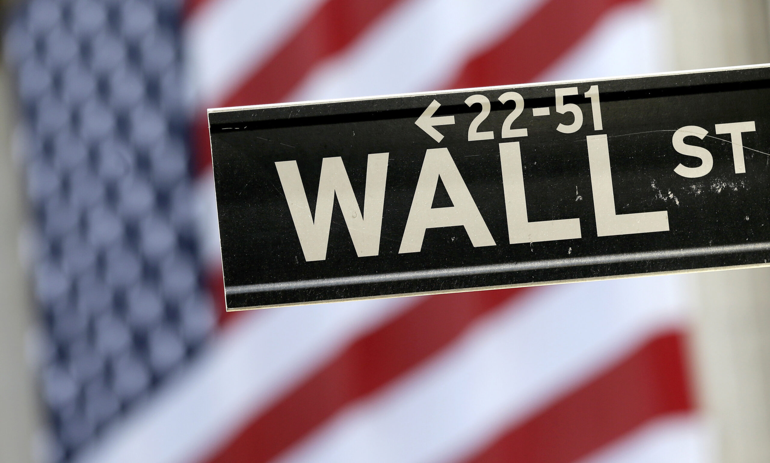 In this Tuesday, Sept. 8, 2015, file photo, a Wall Street street sign is framed by an American flag hanging on the facade of the New York Stock Exchange. (AP Photo/Mary Altaffer, File)