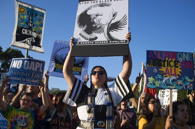 Demonstrators chant and hold up signs as they  protest the Dakota Access Pipeline (Getty/Jim Watson)