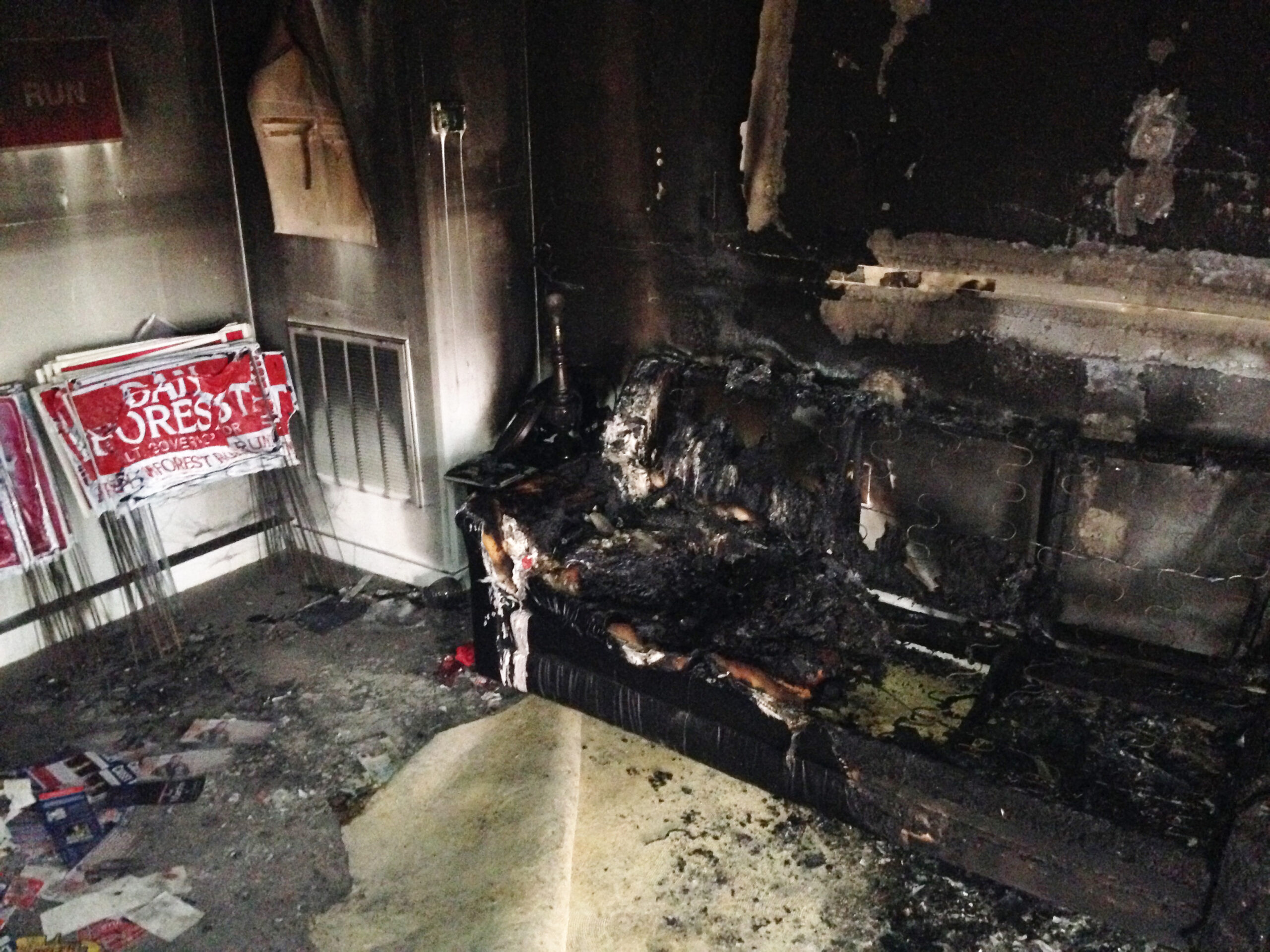 A burned couch is shown next to warped campaign signs at the Orange County Republican Headquarters in Hillsborough, NC on Sunday, Oct. 16 2016. (AP)