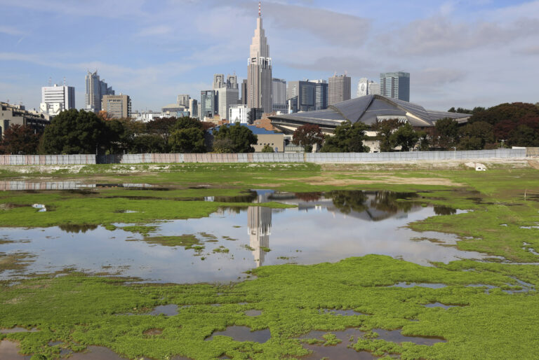 FILE - In this Nov. 16, 2015, file photo, a skyscraper reflects in a pool of water in the site of Japan's National Stadium demolished for the renovation for the 2020 Olympic games as the compound is shown to the media for the first time after the completion of the demolition work in Tokyo. The price tag of the 2020 Tokyo Olympics could exceed 3 trillion yen ($30 billion) unless drastic cost-cutting measures are taken and several key venues are relocated, an expert panel warned Thursday, Sept. 30, 2016, in the latest blow to Japanese organizers. "Naturally, anyone who hears these numbers is alarmed," panel leader Shinichi Ueyama said. (AP Photo/Koji Sasahara, File) (AP)