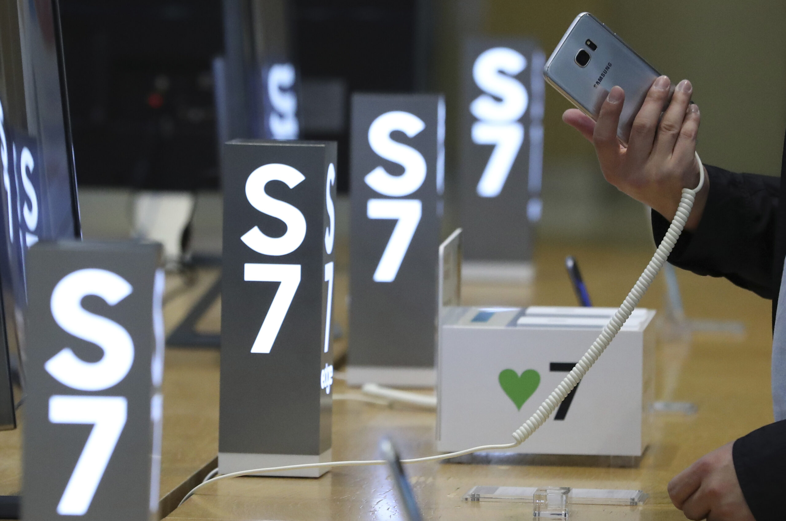A visitor tries out a Samsung Electronics Galaxy S7 Edge smartphone at its shop in Seoul, South Korea, Friday, Oct. 14, 2016. Samsung Electronics said Friday that the discontinuation of the Galaxy Note 7 would cost the company about $3 billion during the current and next quarters, bringing the total cost of the recall to at least $5.3 billion. The company said it will expand sales of two other smartphones released in spring, the Galaxy S7 and Galaxy S7 Edge, quashing rumors that it may try to release updated versions of those devices. (AP Photo/Lee Jin-man) (AP)
