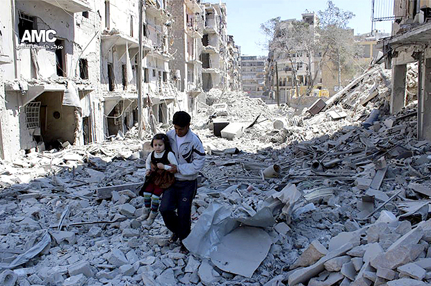 Syrian man holding a girl as he stands on the rubble of houses that were destroyed by Syrian government forces air strikes in Aleppo, Syria (AP)