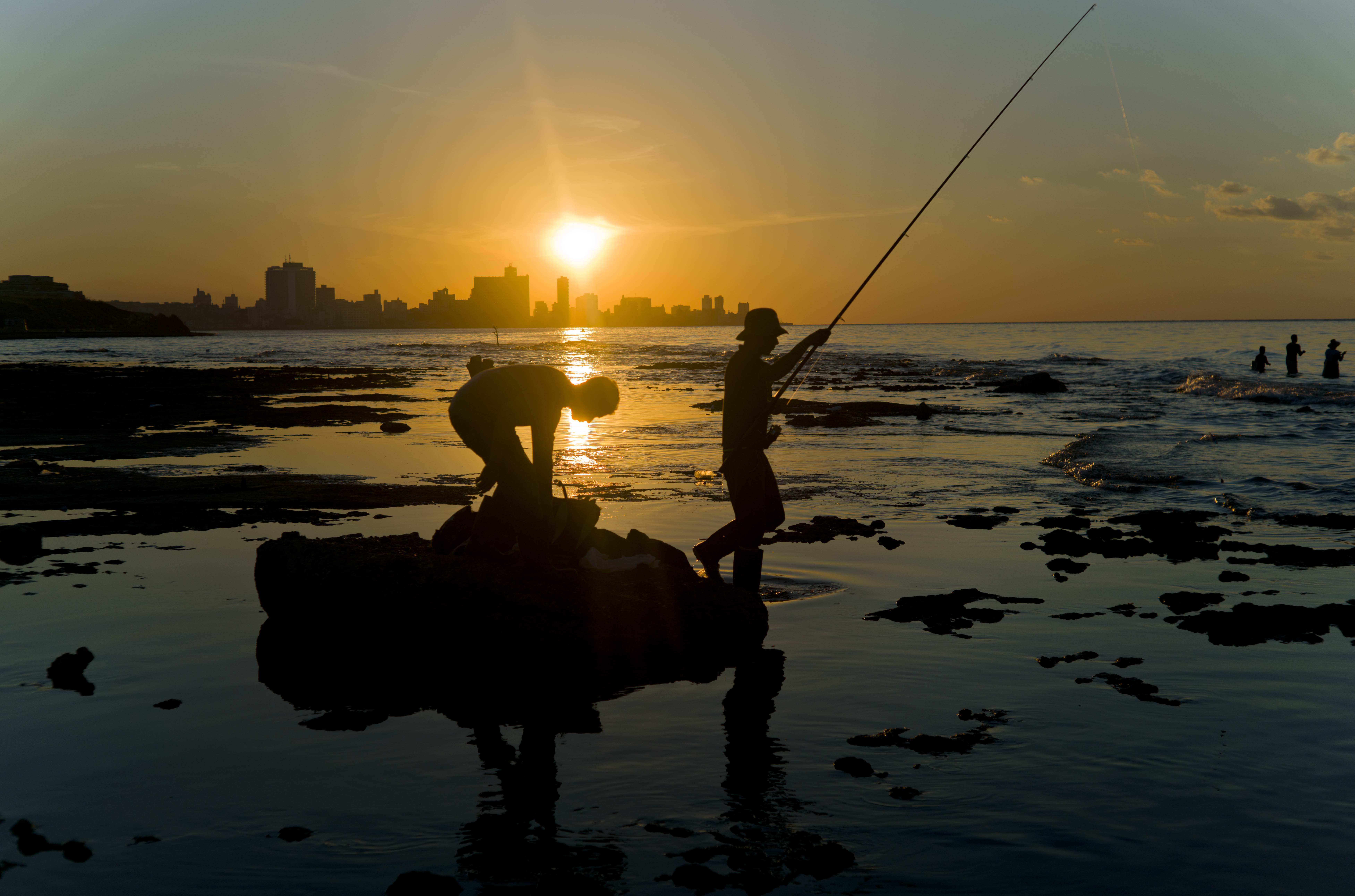 In this Nov. 11, 2016 photo, fishermen throw their fishing rods from Chivo beach as the sun sets in Havana, Cuba. Cuba has been renowned for its fishing at least since the days of Ernest Hemingway, and foreigners by the thousands come each year to fish in waters largely protected by Cuba’s lack of development. () (AP Photo/Ramon Espinosa)
