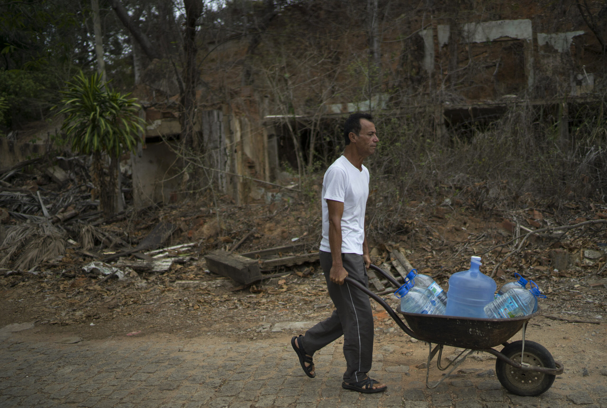 In this Oct. 11, 2016 photo, Lazimar Caliari pushes a wheelbarrow loaded with gallons of well water, in Colatina, Brazil. The 53-year-old musician is concerned about the quality of the water in the Doce River a year after a dam of mine waste broke, sending metal-laden mud into the Doce. "The mayor doesn't drink the water form the Doce River, so why should I have to drink it too?" asks Caliari. (AP Photo/Leo Correa) (AP)