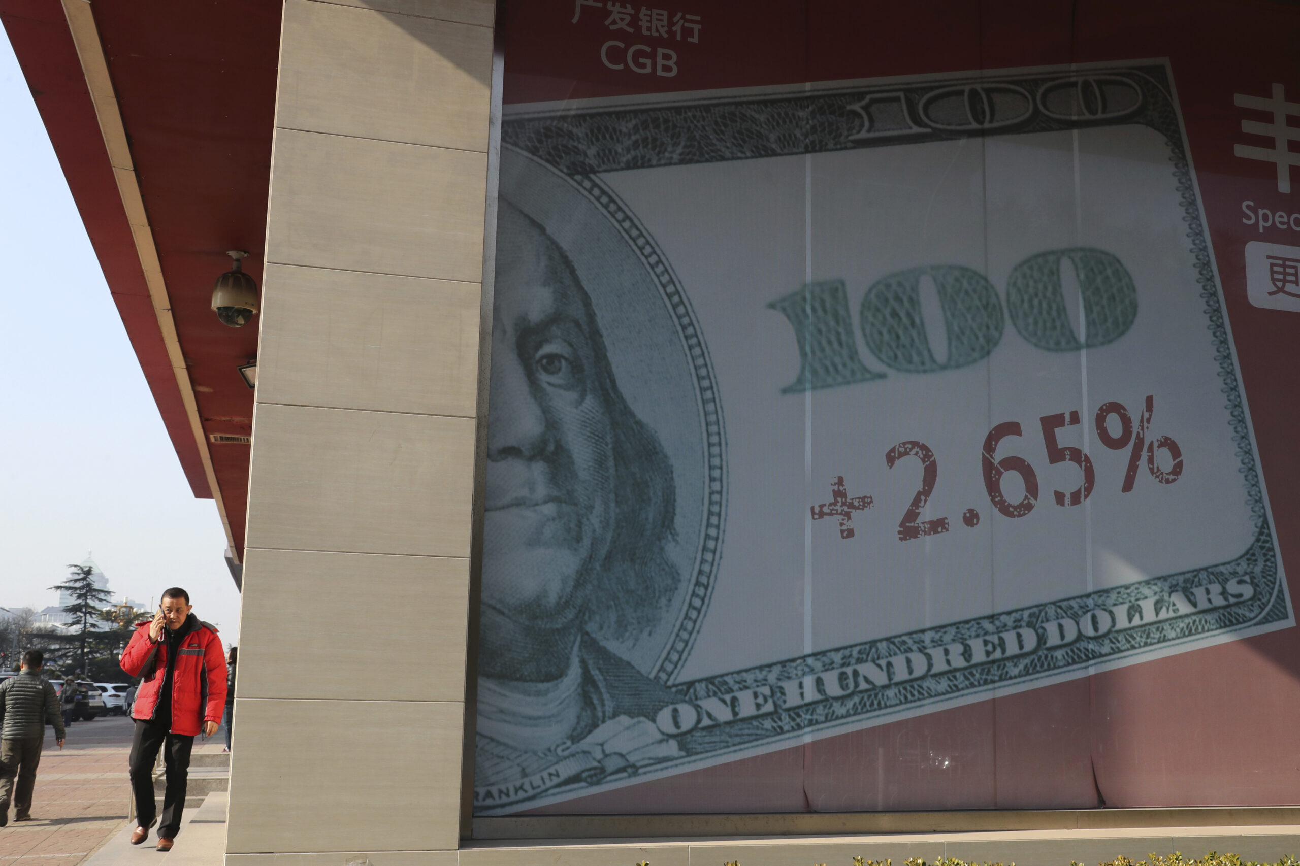 A man walks past a billboard with the U.S. currency displayed on its outside a bank in Beijing, China, Thursday, Nov. 24, 2016. (AP)
